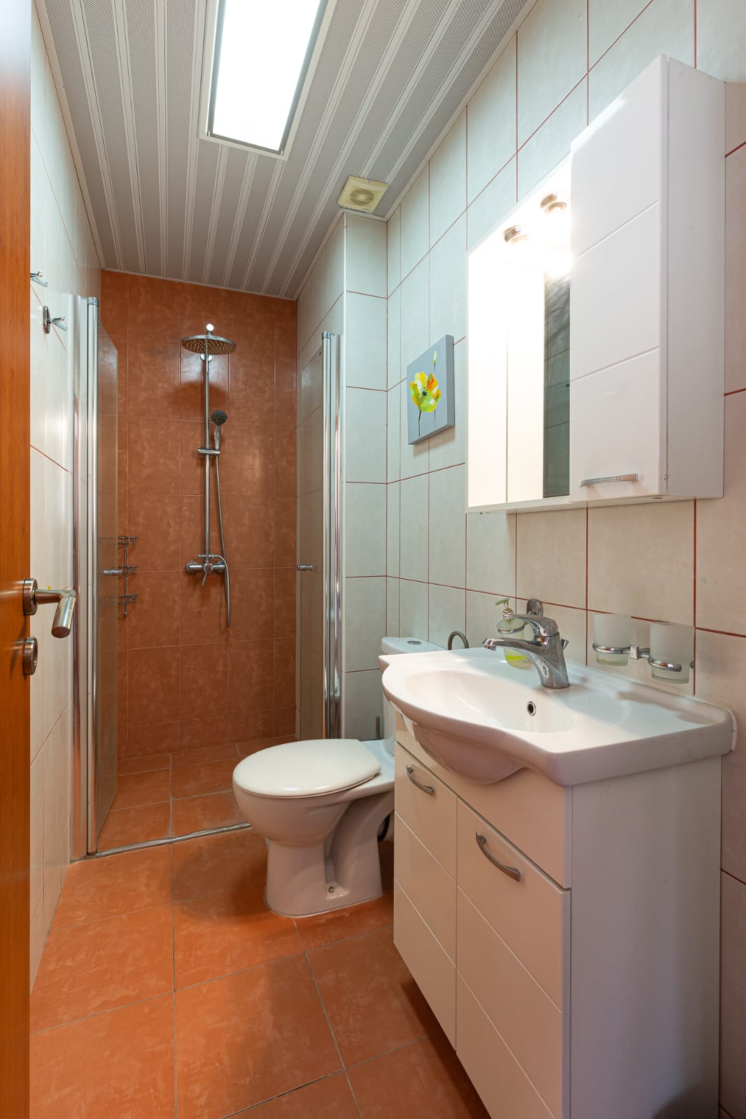 Modern, space-efficient bathroom in Ulcinj with orange tiles, premium fixtures, glass shower. Invest via montenegro-listings.me by ekosphere doo.