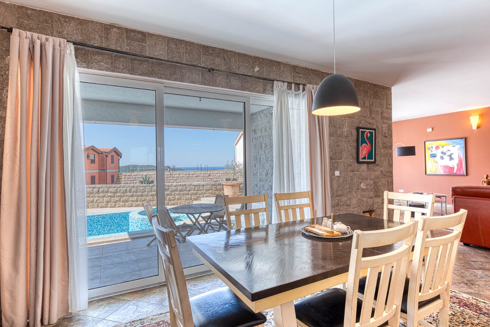 Elegant dining area with stone walls, designer lighting, pool access, and stylish interiors&mdash;invest in Ulcinj Montenegro real estate today!.