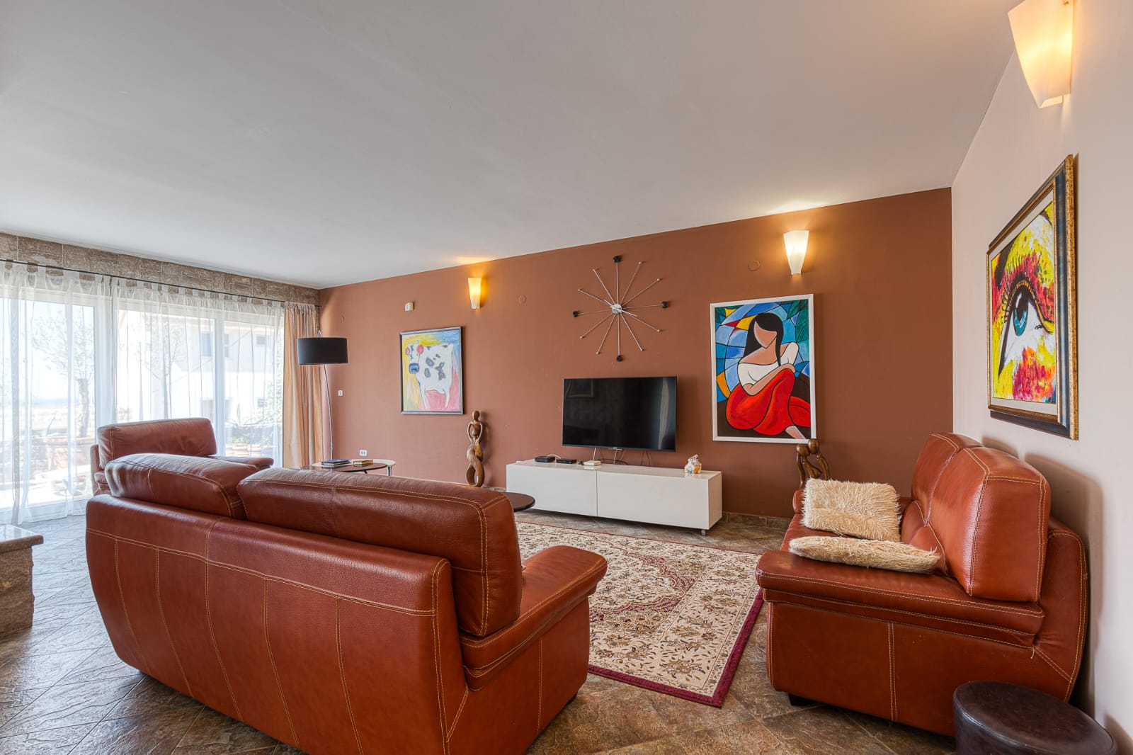 Stylish Ulcinj living room: brown leather sofas, large windows, premium details. Invest in Montenegro real estate at montenegro-listings.me by ekosphere doo.