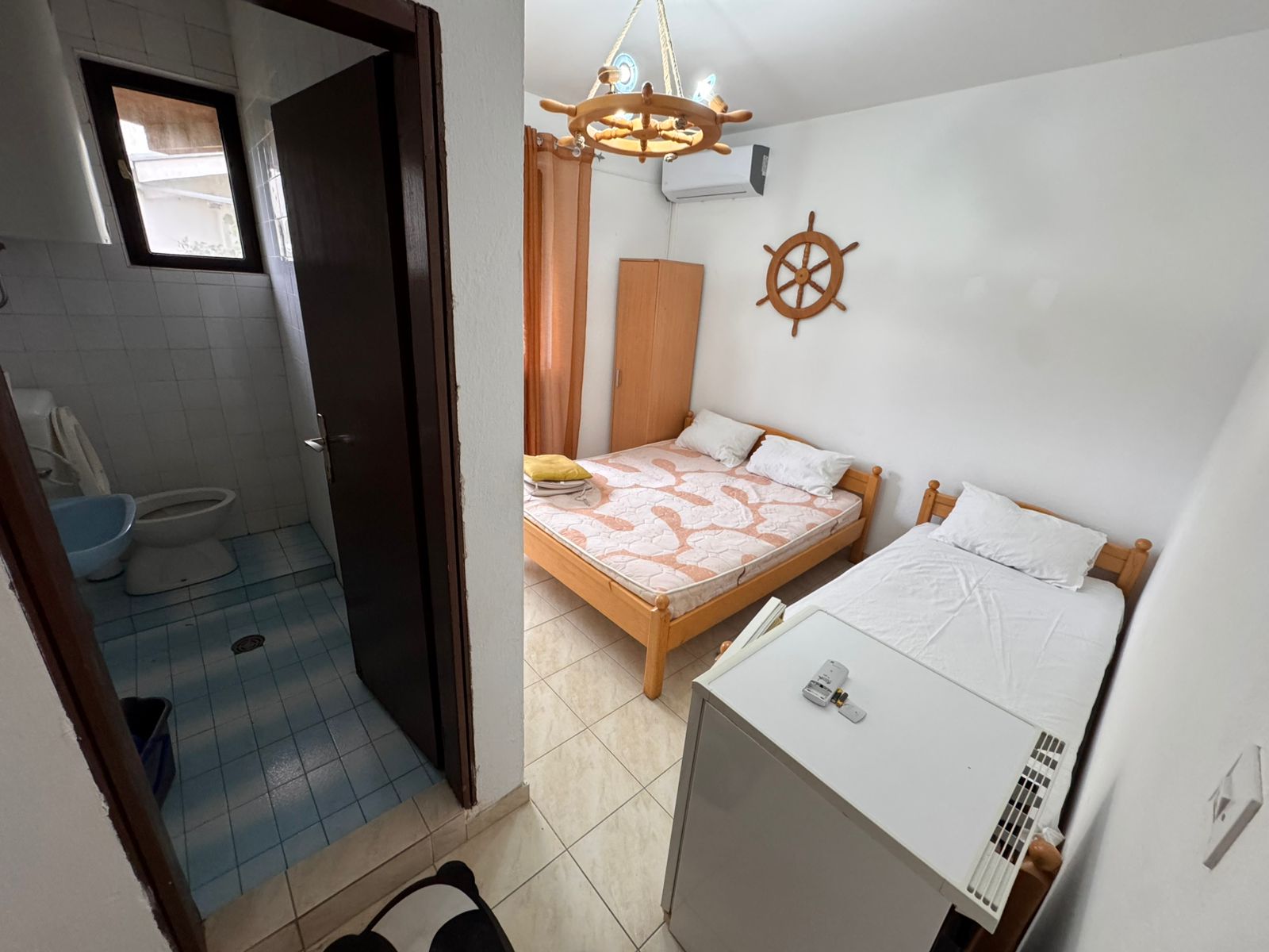 Charming Ulcinj hotel room: double & single beds, mini fridge, unique decor, ensuite with blue tiles. Invest via montenegro-listings.me.