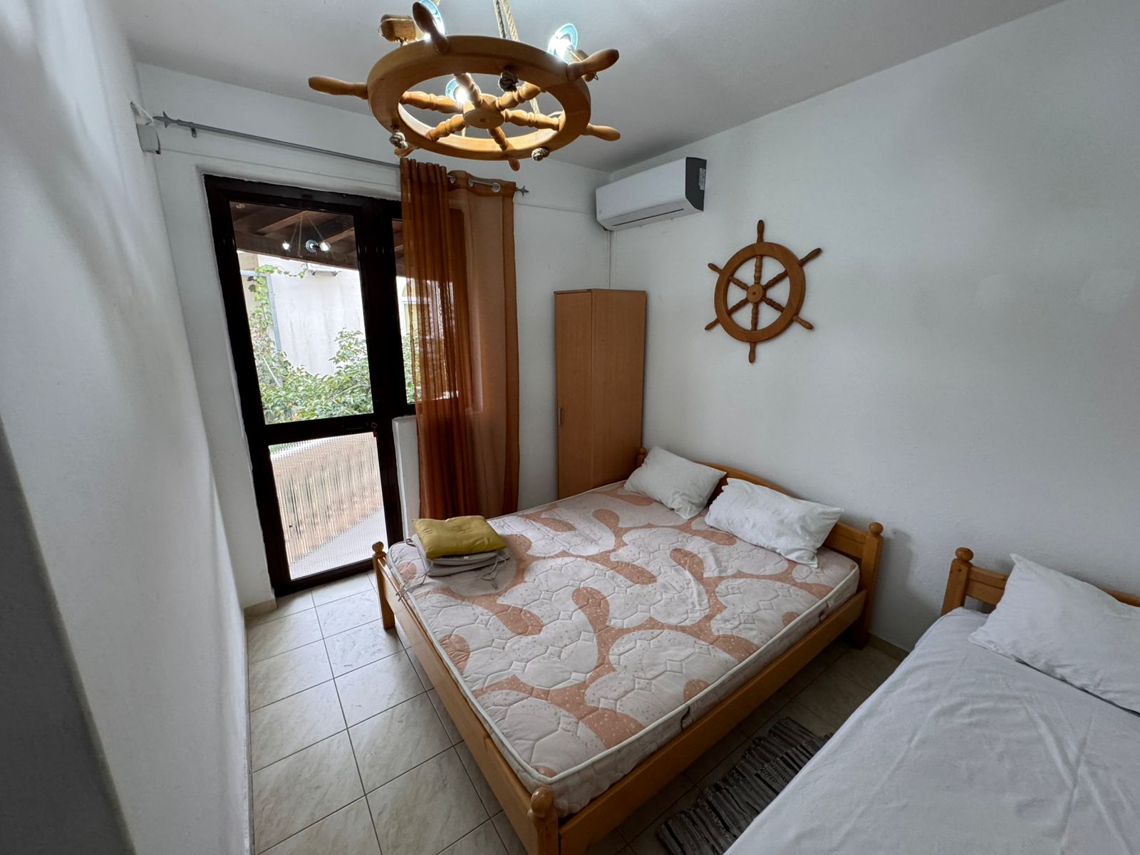 Charming Ulcinj bedroom with double and single beds, nautical details, and private glass door—ideal Montenegro real estate investment.