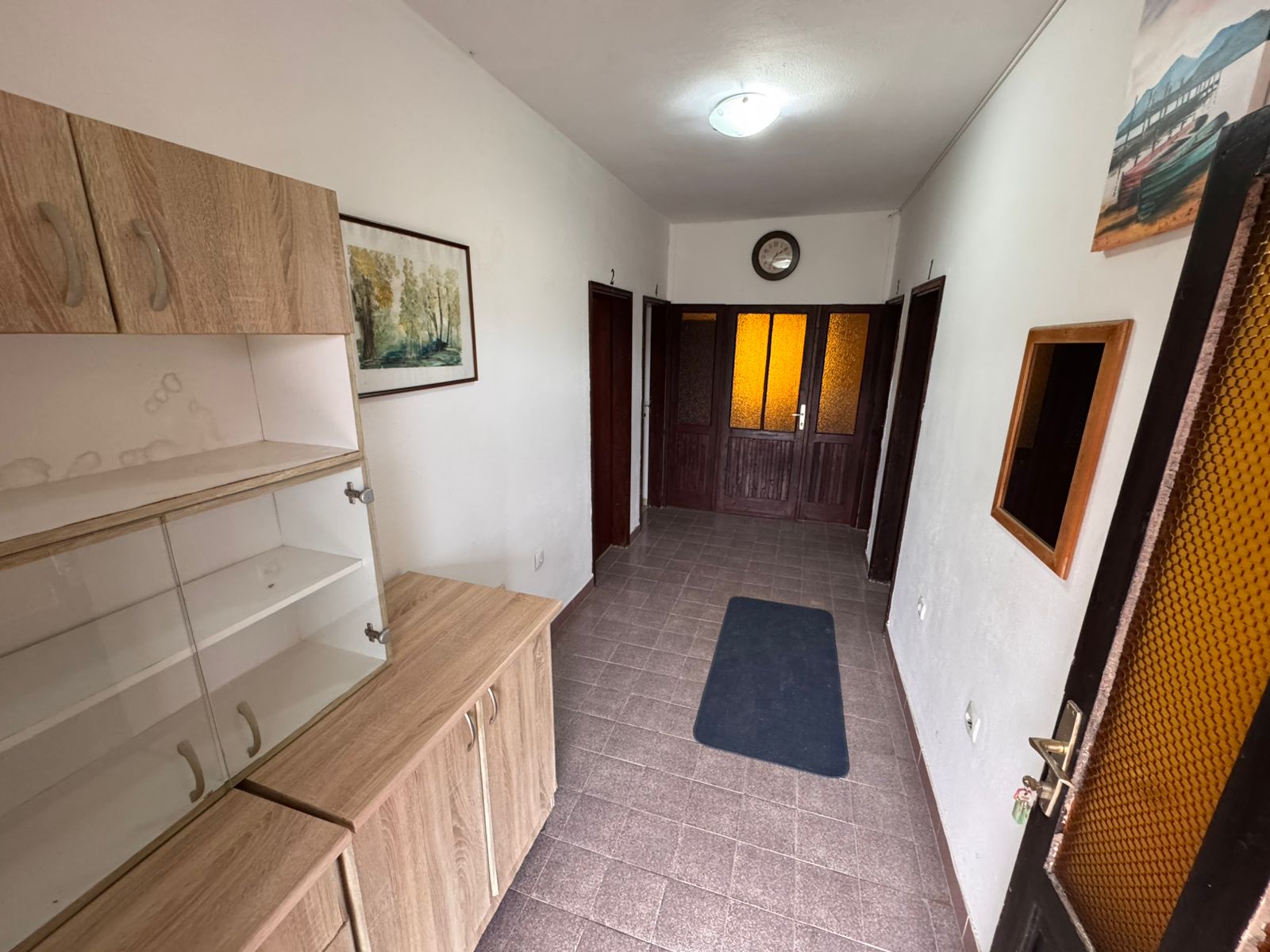 Elegant Ulcinj hallway with brown tiled floors, wood cabinets, art accents—ideal Montenegro investment via montenegro-listings.me by ekosphere doo.