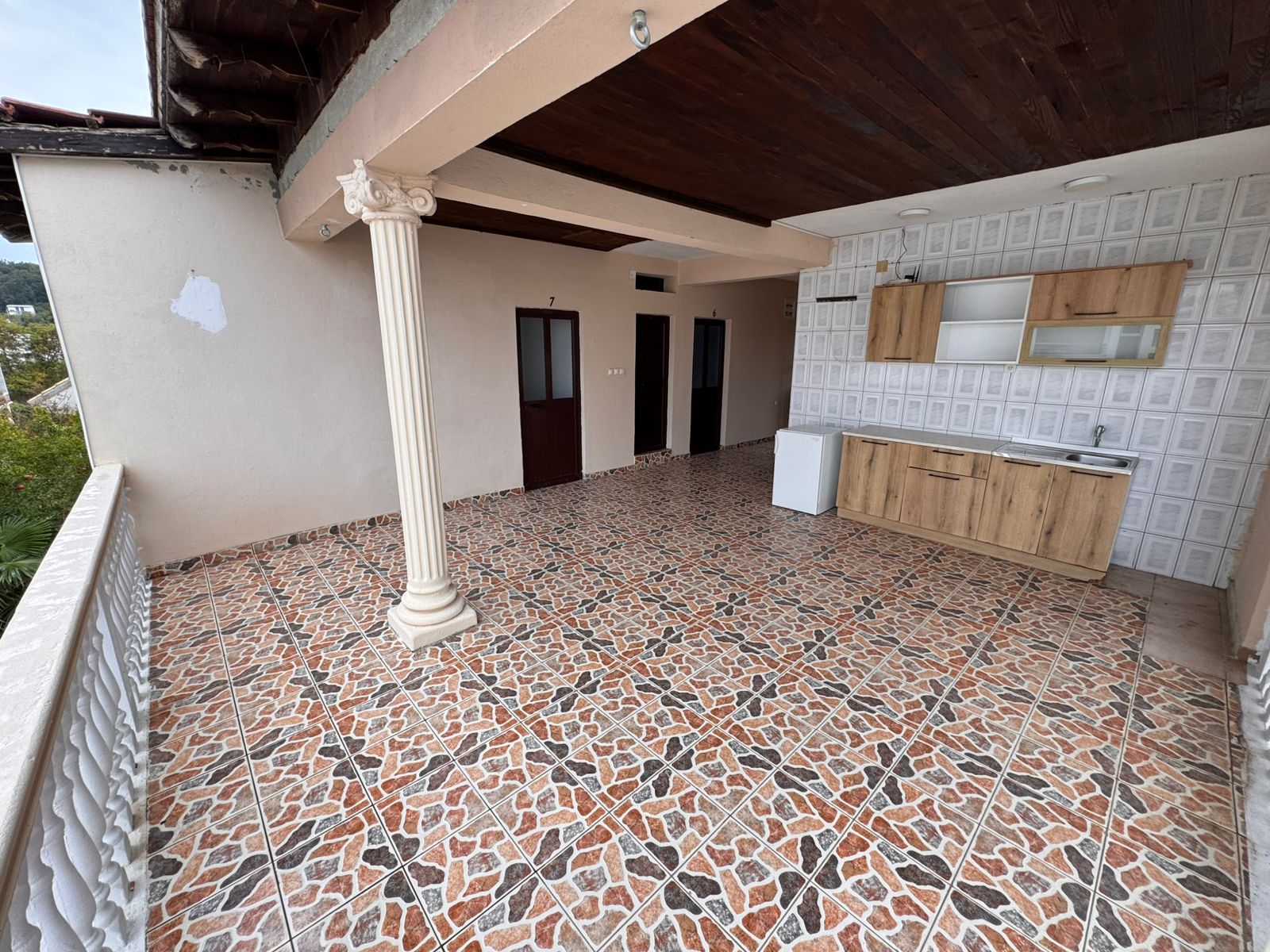 Stylish covered terrace in Ulcinj, Montenegro—patterned tiles, wooden ceiling, kitchenette. Prime investment via montenegro-listings.me.