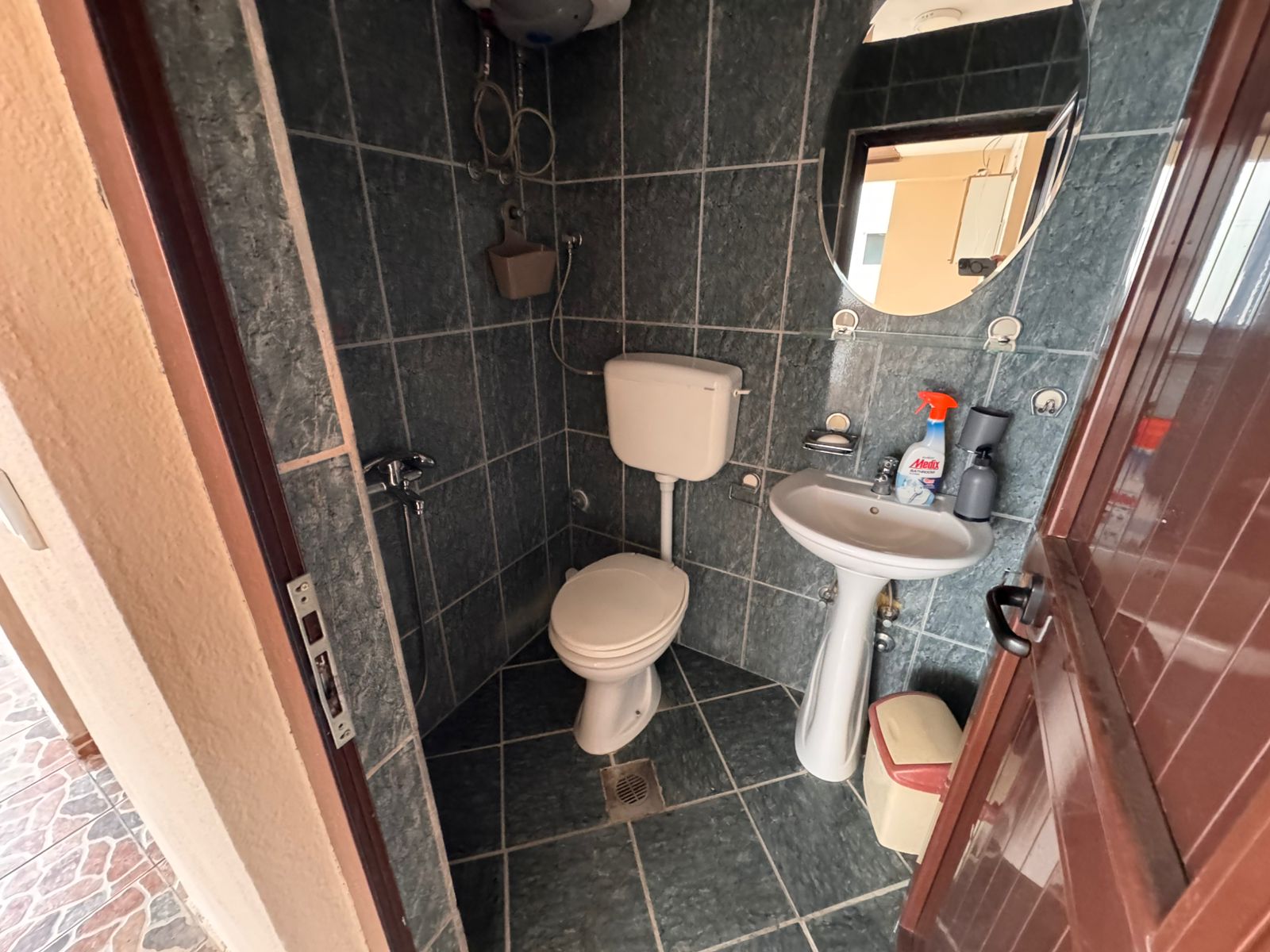 Modern tiled bathroom in Ulcinj with toilet, pedestal sink, mirror, water heater; prime real estate on montenegro-listings.me by ekosphere doo.