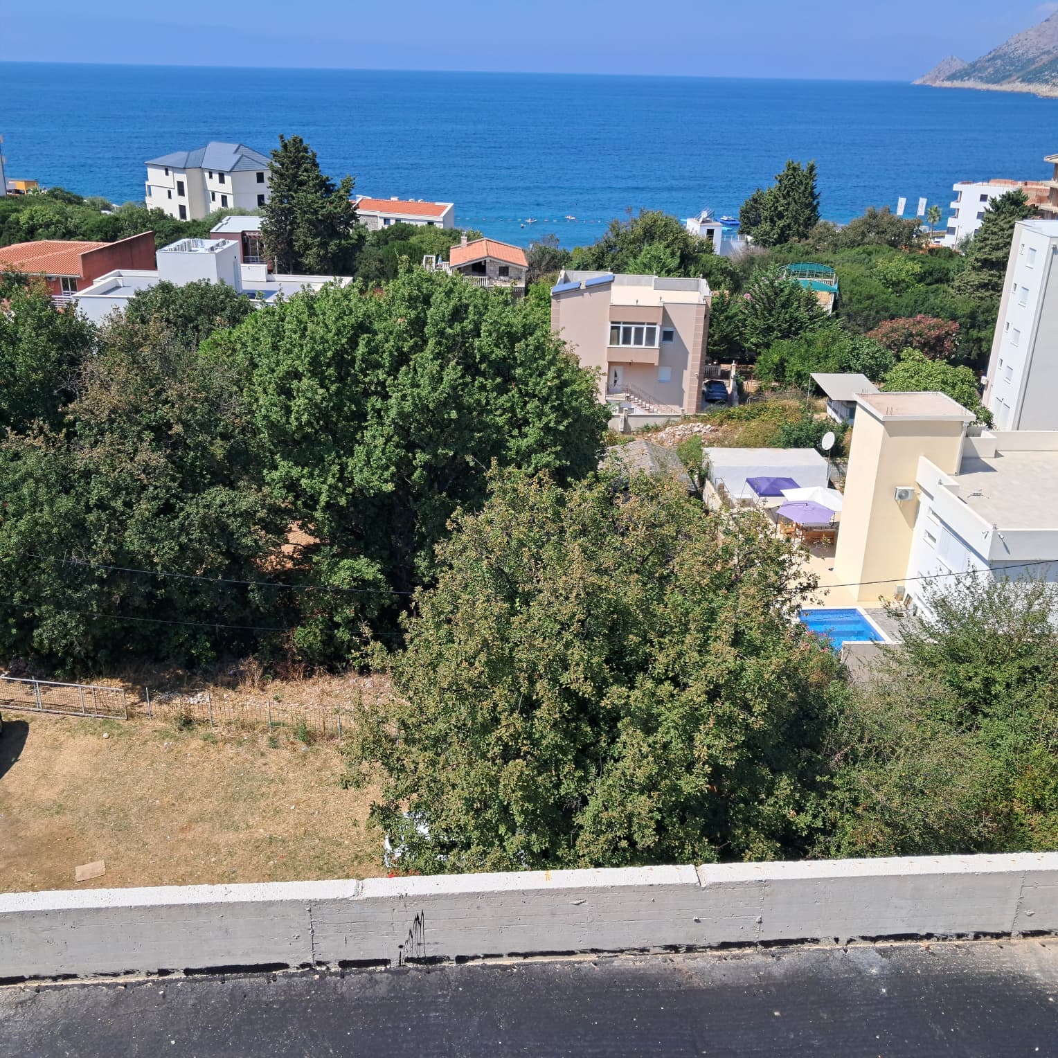 Stunning aerial view of Ulcinj: coastal homes, lush trees, sea views & pool—exclusive Montenegro real estate by ekosphere doo.