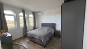 Elegant Ulcinj bedroom with gray furnishings, wood floors, arched windows—premium Montenegro real estate by ekosphere doo.