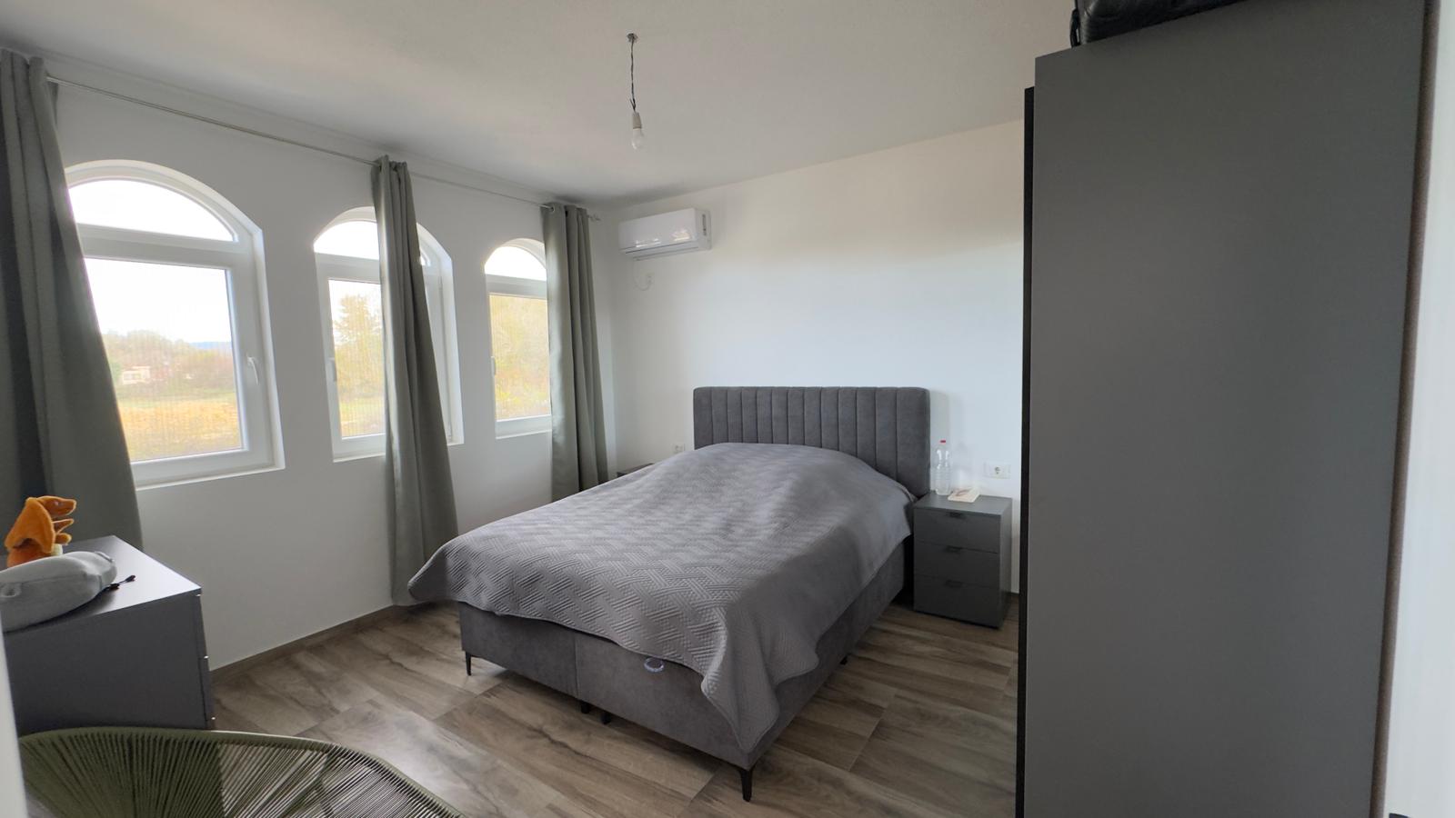 Elegant Ulcinj bedroom with gray furnishings, wood floors, arched windows&mdash;premium Montenegro real estate by ekosphere doo.