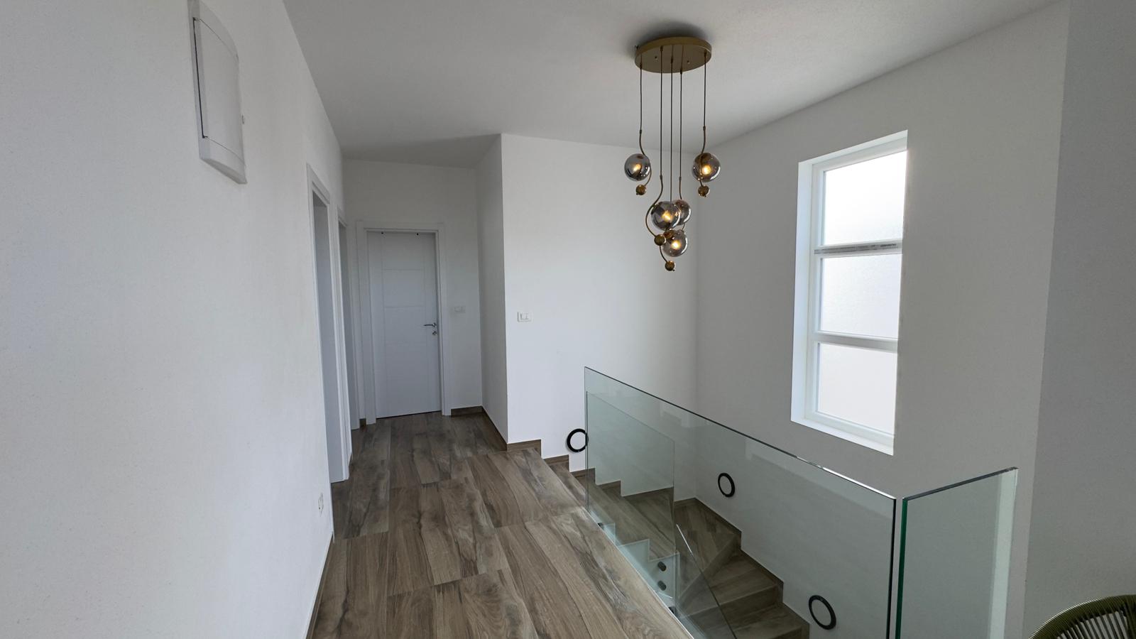 Stunning modern hallway with premium wooden floors, glass railing, elegant lighting&mdash;prime Ulcinj real estate by ekosphere doo.