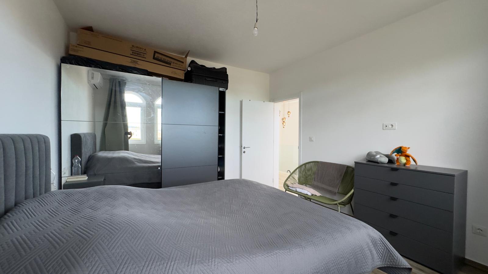 Modern Ulcinj bedroom with stylish gray bed, mirrored wardrobe, and ample storage&mdash;exclusive on montenegro-listings.me by ekosphere doo.