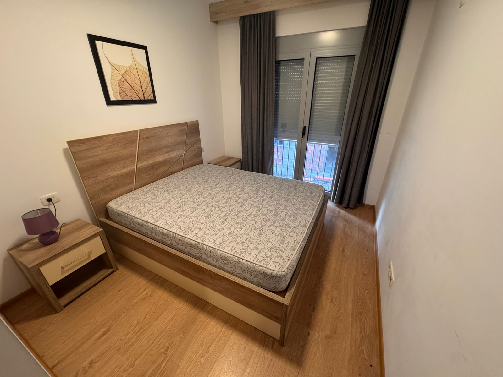 Stylish Ulcinj bedroom with wooden bed, elegant flooring, modern nightstand, and bright window&mdash;ideal real estate at montenegro-listings.me by ekosphere doo.