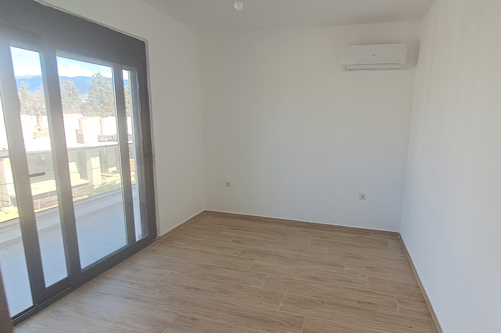 Bright, modern Ulcinj apartment: spacious room, premium wood flooring, large balcony doors, AC unit. Invest via montenegro-listings.me (ekosphere doo).