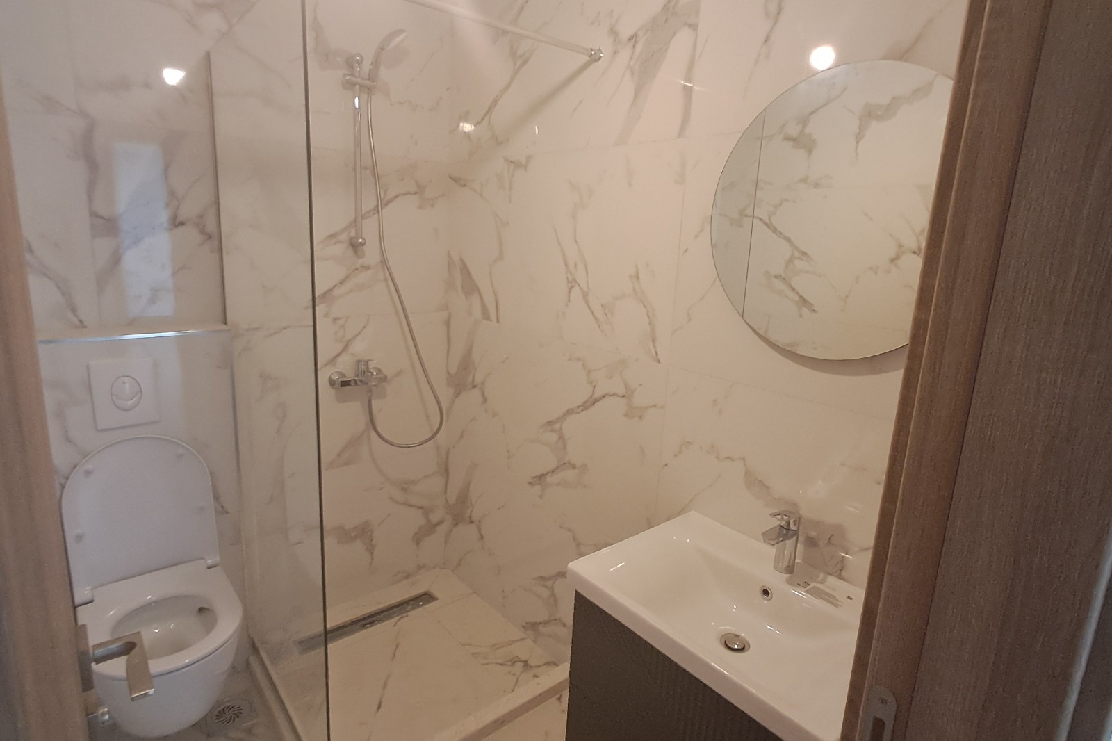 Modern bathroom in Ulcinj with marble-patterned walls, walk-in shower, and premium finishes—exclusive Montenegro-listings.me by ekosphere doo.