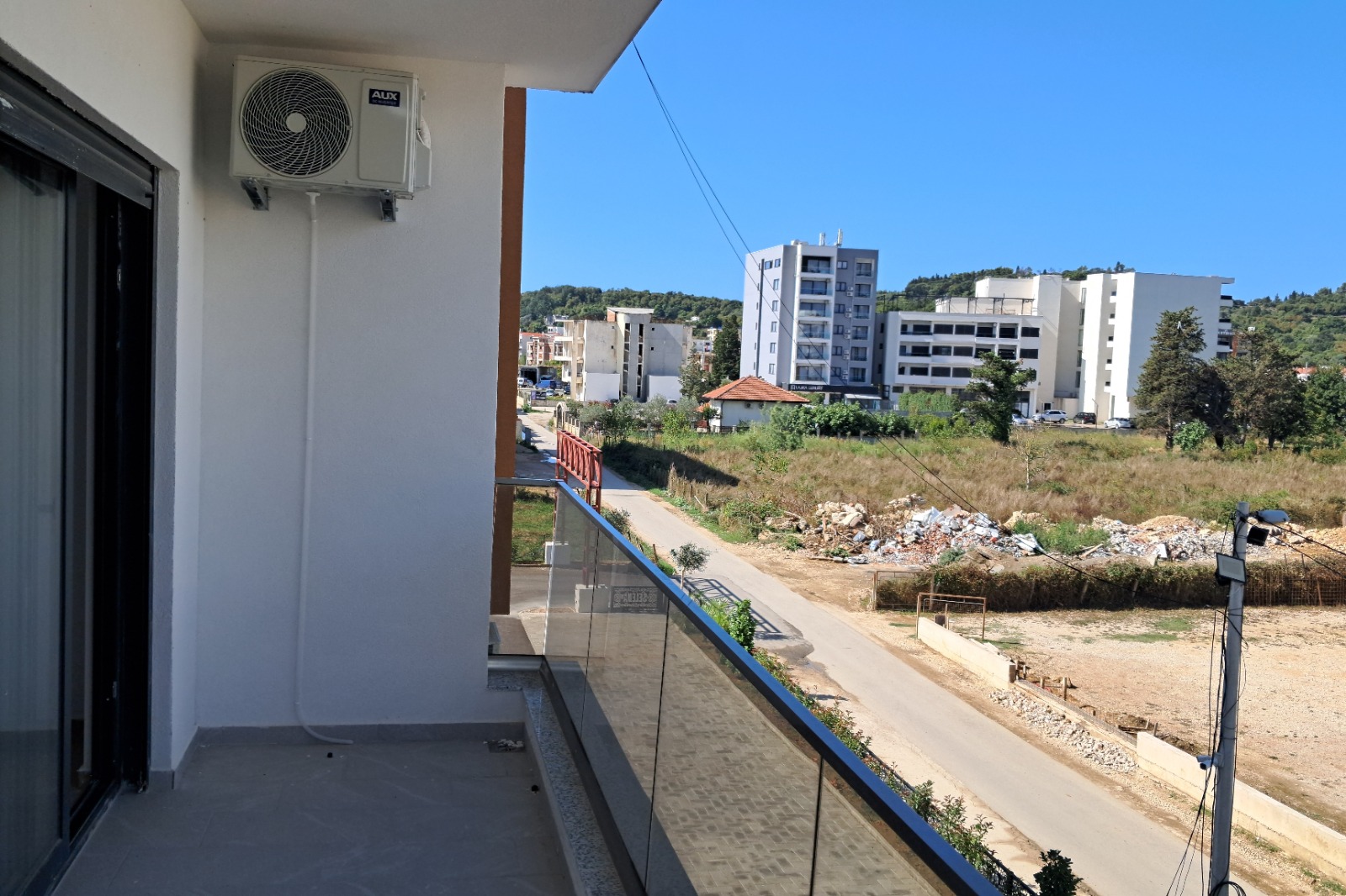 Modern balcony view with glass railing, air conditioning, and cityscape—prime Ulcinj investment on montenegro-listings.me by ekosphere doo.
