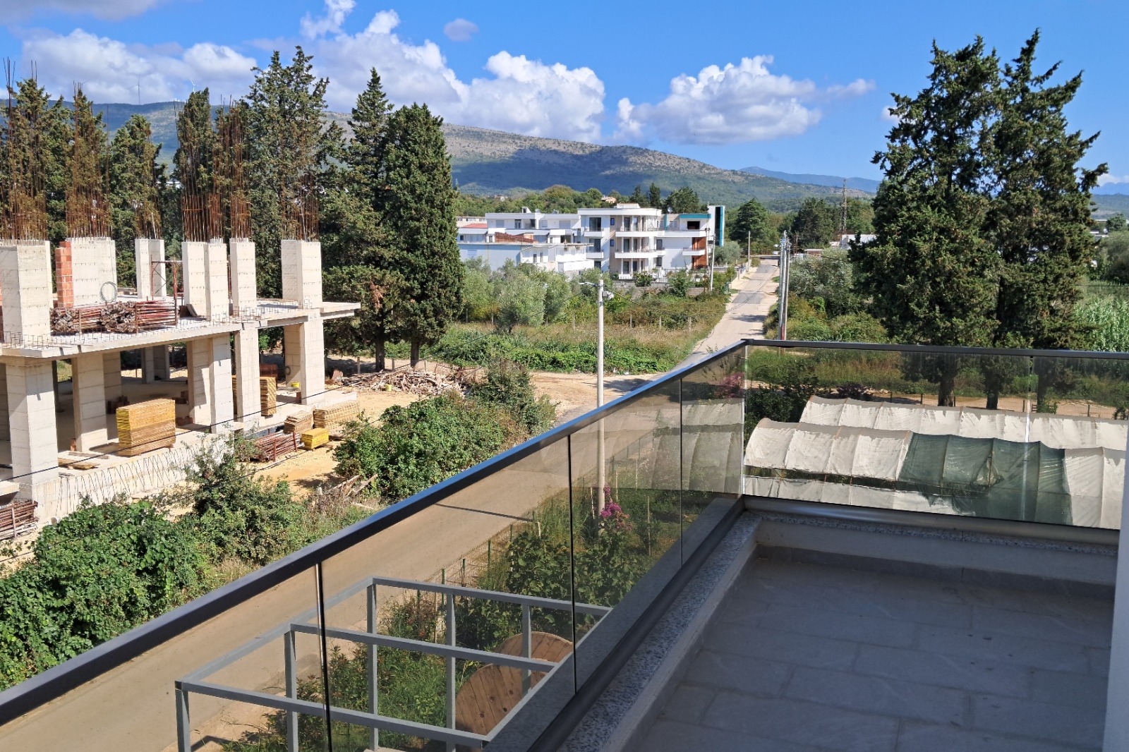 Stunning Ulcinj investment view: modern homes, lush greenery, mountain backdrop. Exclusive at montenegro-listings.me by ekosphere doo.