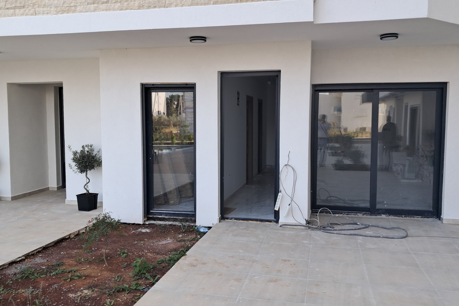 Modern Ulcinj property: sleek white-walled building with glass door, large window, open entry. Exclusive on montenegro-listings.me by ekosphere doo.