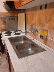 Modern Ulcinj kitchen with double stainless steel sink, electric stove, and microwave—ideal Montenegro investment. Eksphere doo.