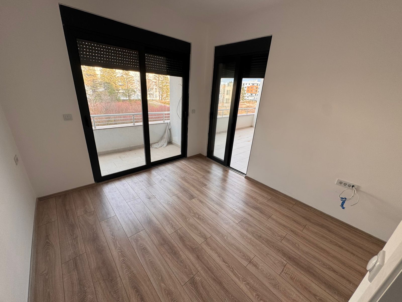 Spacious sunlit room in Ulcinj, Montenegro, featuring modern wood floors, balcony access, ideal for investment via montenegro-listings.me.