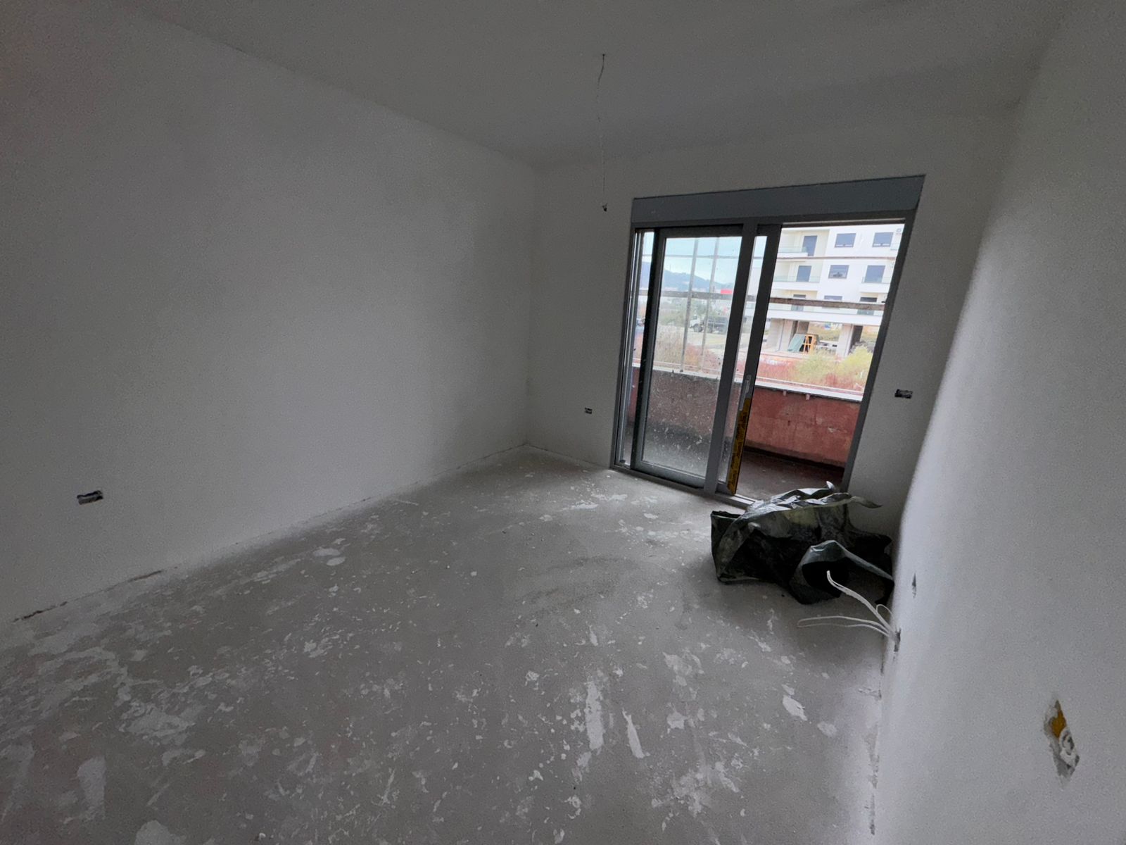 Spacious unfinished room in Ulcinj, Montenegro with white walls, concrete floors, and balcony access&mdash;prime investment via montenegro-listings.me.