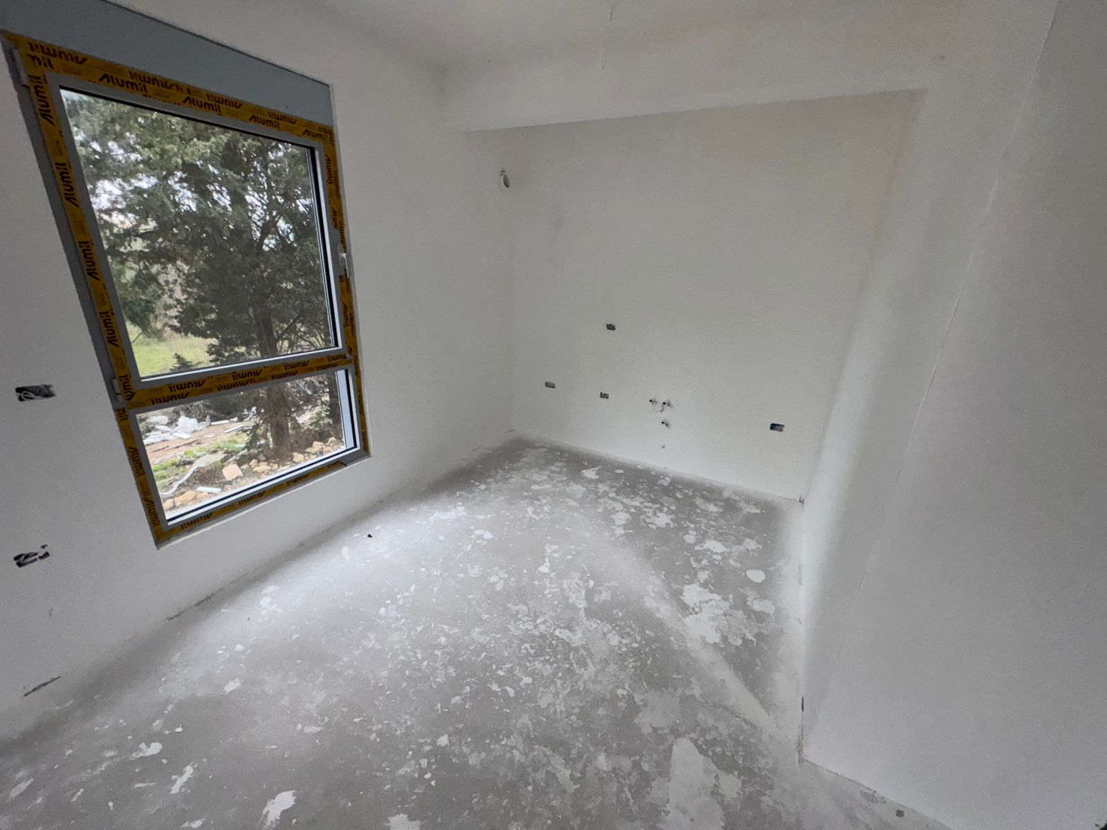 Unfinished room with white walls, concrete floor, large window&mdash;ideal for custom design in Ulcinj. Exclusive at montenegro-listings.me by ekosphere doo.