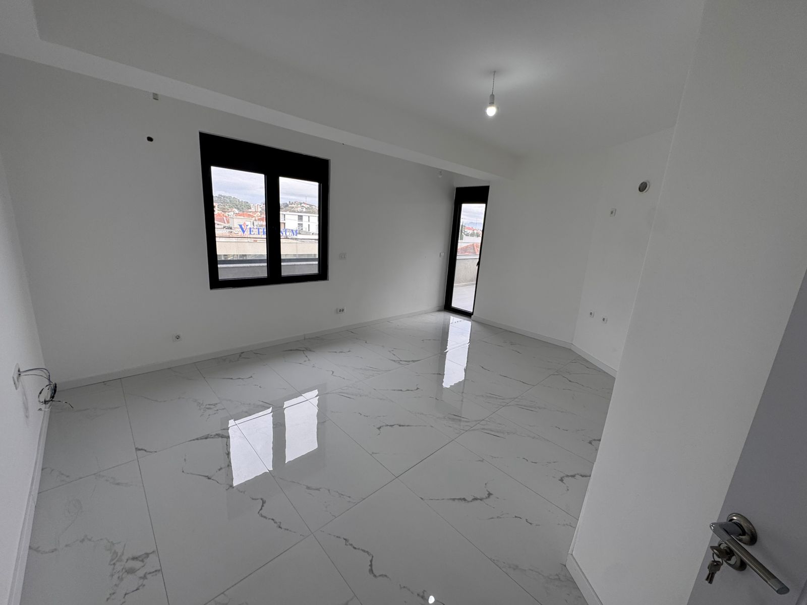 Bright, modern room in Ulcinj, Montenegro: glossy tiled floors, balcony access. Investment opportunity on montenegro-listings.me by ekosphere doo.