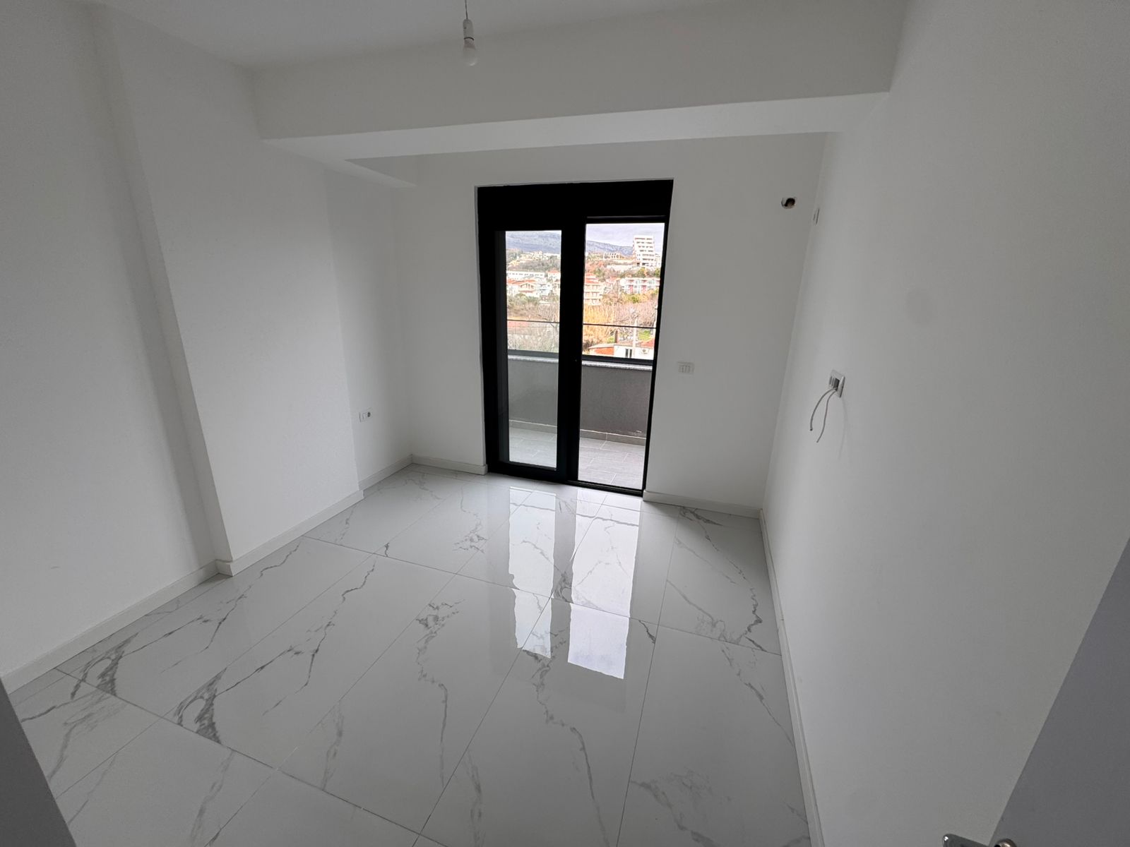 Bright, spacious room in Ulcinj with tiled floor, white walls, balcony access&mdash;prime Montenegro real estate from ekosphere doo.