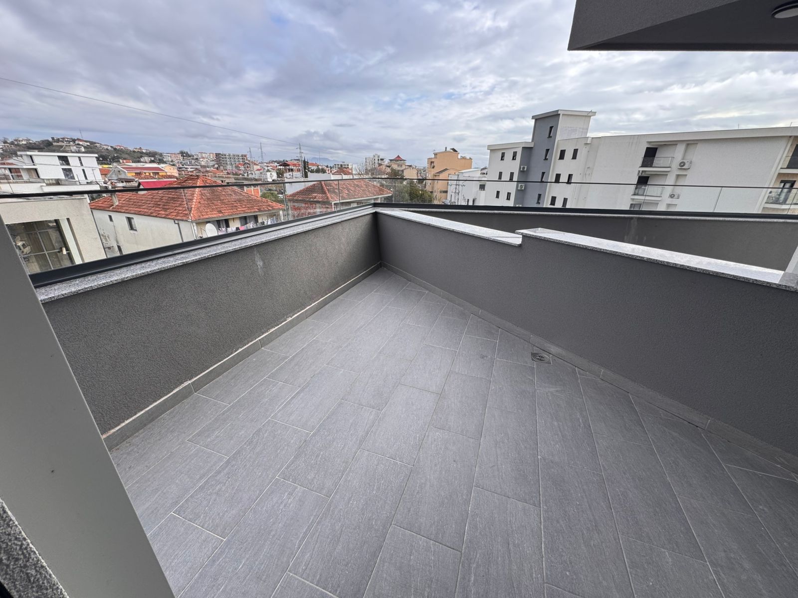 Modern balcony with elegant gray tiles and city views&mdash;premium Ulcinj real estate by ekosphere doo, montenegro-listings.me.