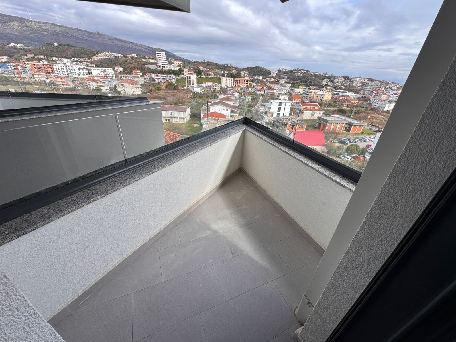 Bright, tiled balcony in Ulcinj with panoramic views over hills and residences&mdash;ideal Montenegro property investment. Explore montenegro-listings.me by ekosphere doo.