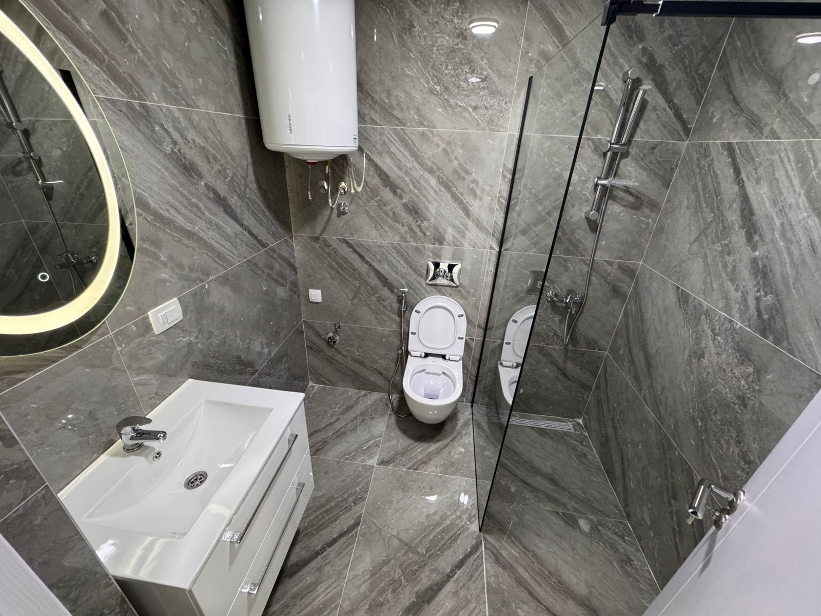 Luxury bathroom in Ulcinj, Montenegro: sleek gray marble, wall-mounted toilet, bidet, modern sink&mdash;exclusive via montenegro-listings.me.