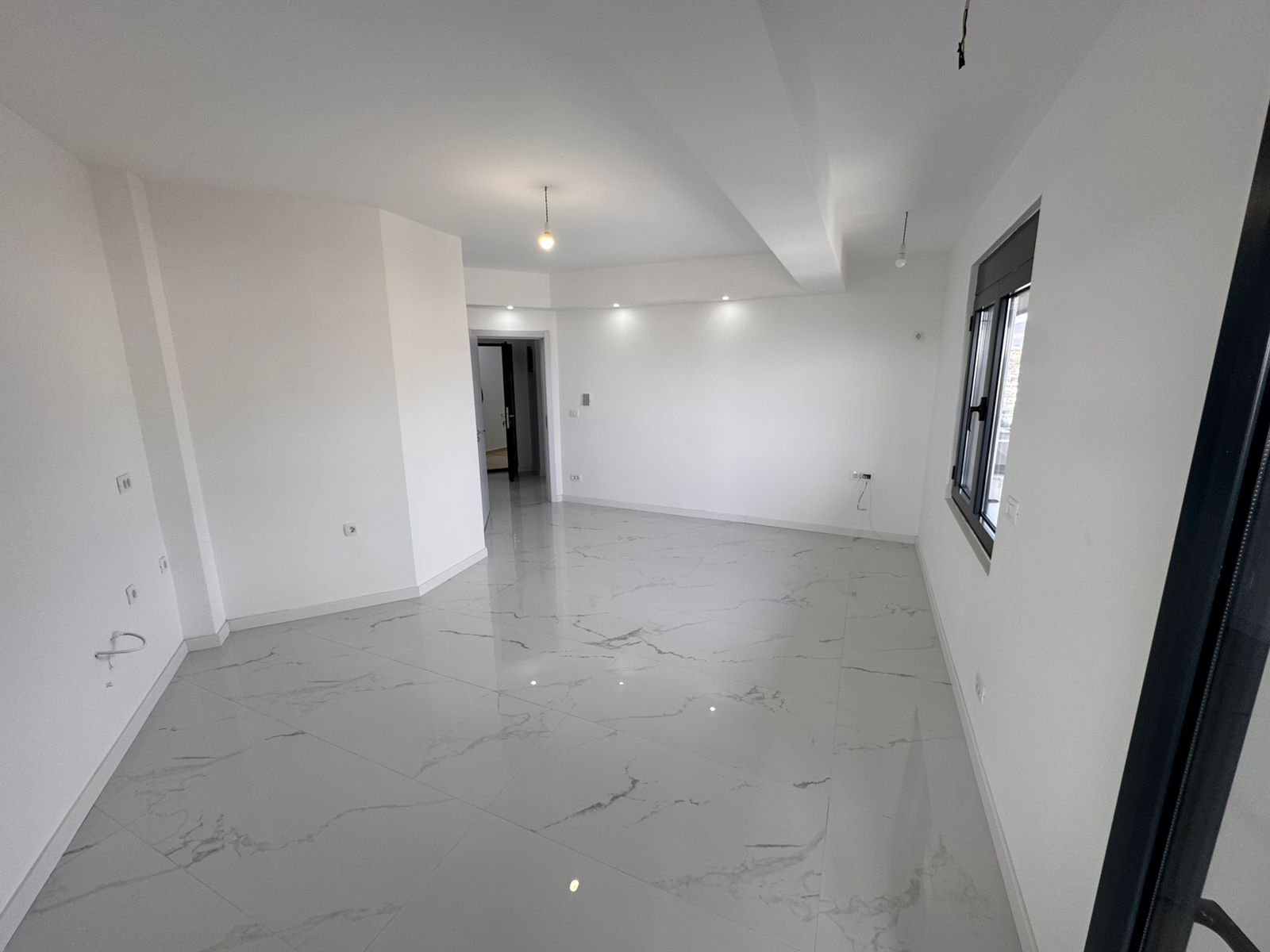 Helles, modernes Zimmer mit elegantem Marmorfliesenboden, gro&szlig;em Fenster und offenem Grundriss-eine erstklassige Immobilie in Ulcinj via montenegro-listings.me.
