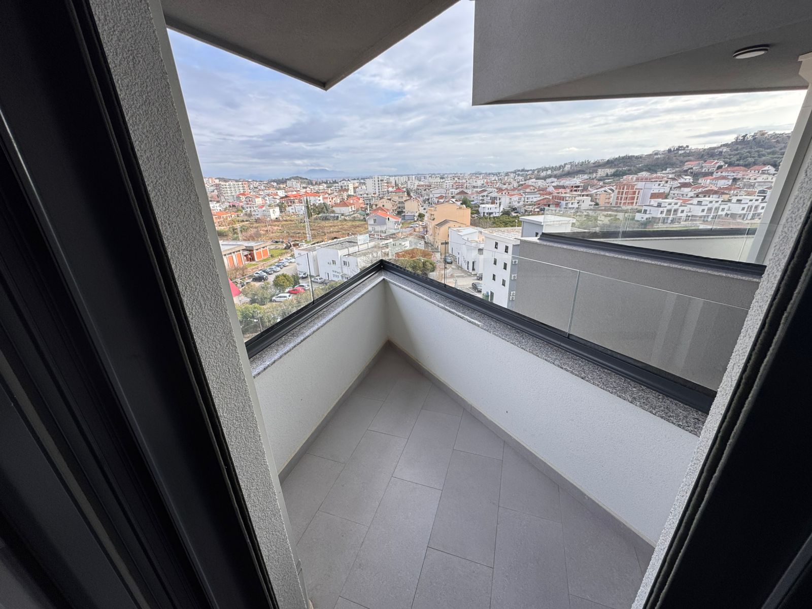 Modern balcony with light grey tiles, white walls, and stunning Ulcinj city views&mdash;prime investment via montenegro-listings.me by ekosphere doo.