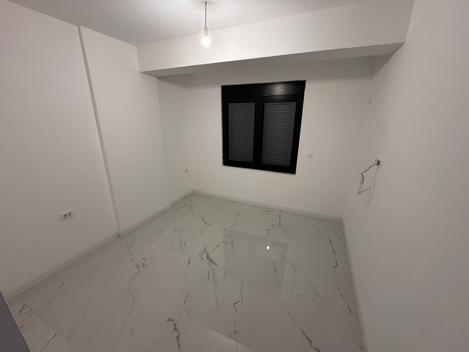 Bright, modern space with white walls, marble-patterned tiles, black-framed window&mdash;ideal Ulcinj investment via montenegro-listings.me.