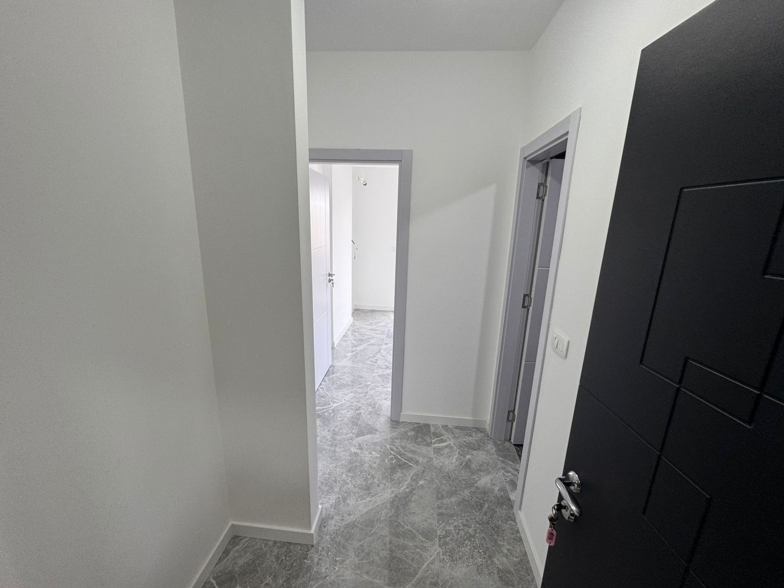Eleganter Flur mit hochwertigen grauen Marmorb&ouml;den, wei&szlig;en W&auml;nden und modernen T&uuml;ren - eine ideale Immobilieninvestition in Ulcinj von ekosphere doo.