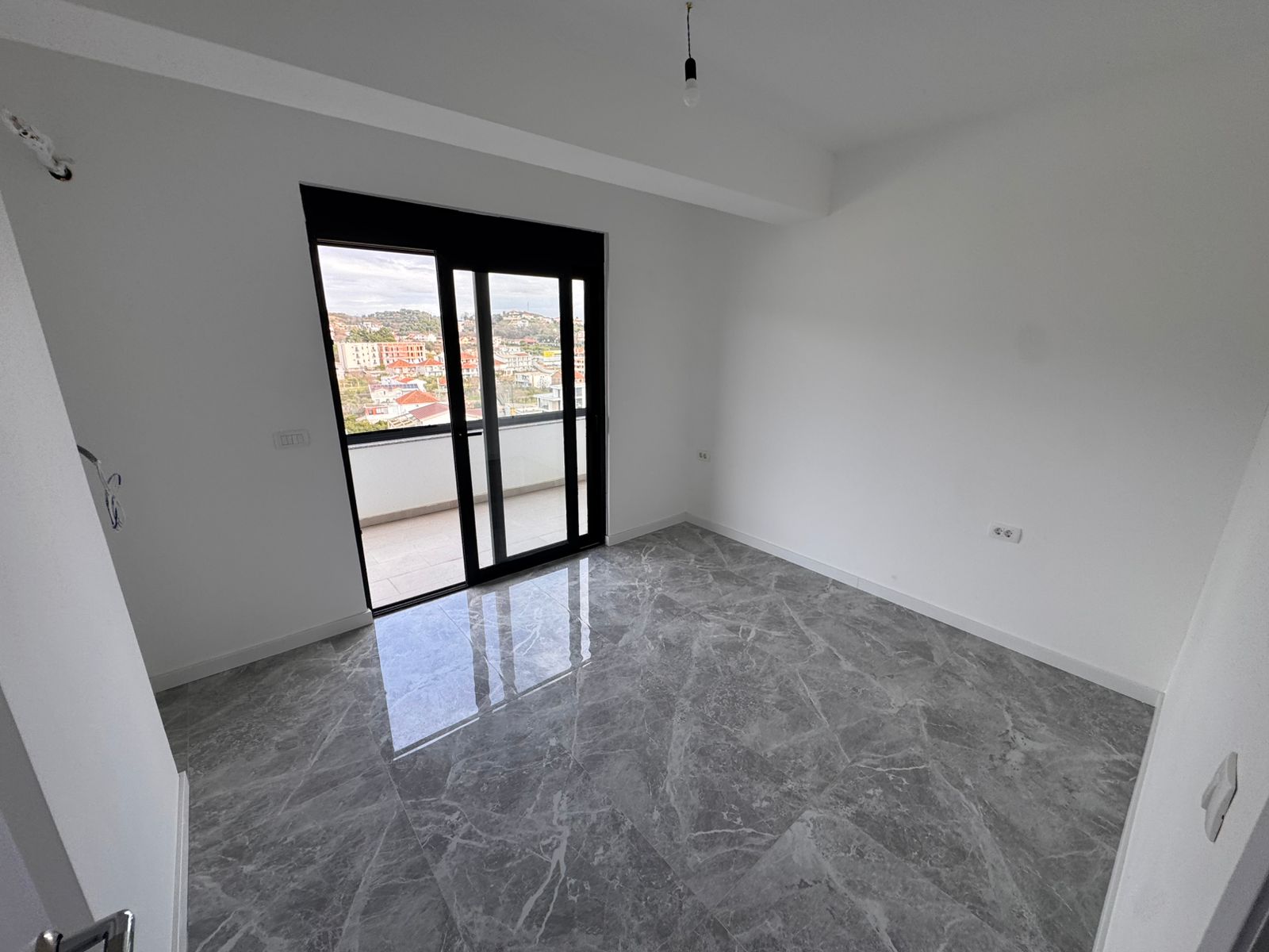 Modern unfurnished apartment in Ulcinj with gray marble floors, bright interiors, and city-view balcony. Exclusive to montenegro-listings.me by ekosphere doo.