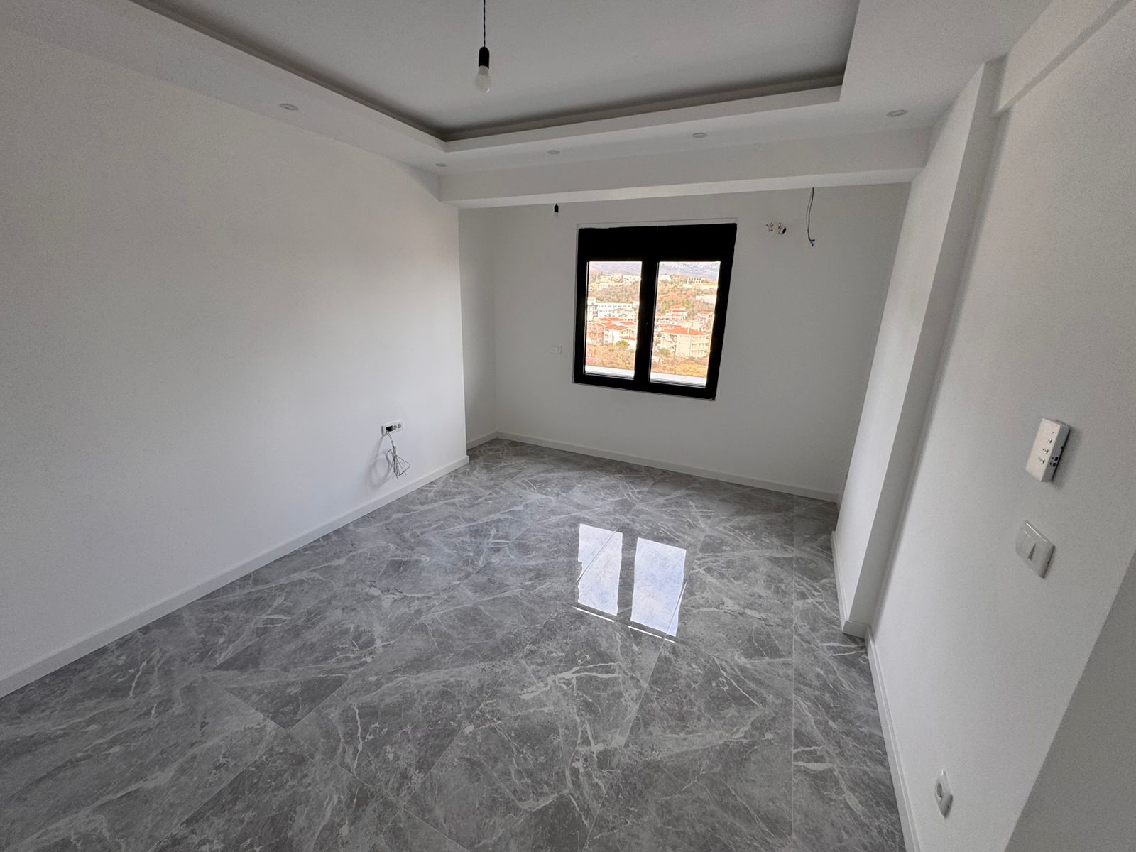 Bright unfurnished room in Ulcinj, Montenegro with white walls, marble tiles, and large window&mdash;top investment on montenegro-listings.me by ekosphere doo.
