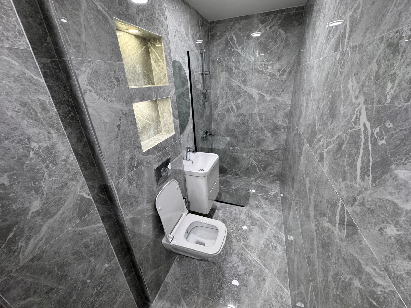 Luxurious gray marble bathroom in Ulcinj, Montenegro&mdash;glass shower, sleek fixtures. Exclusive at montenegro-listings.me by ekosphere doo.