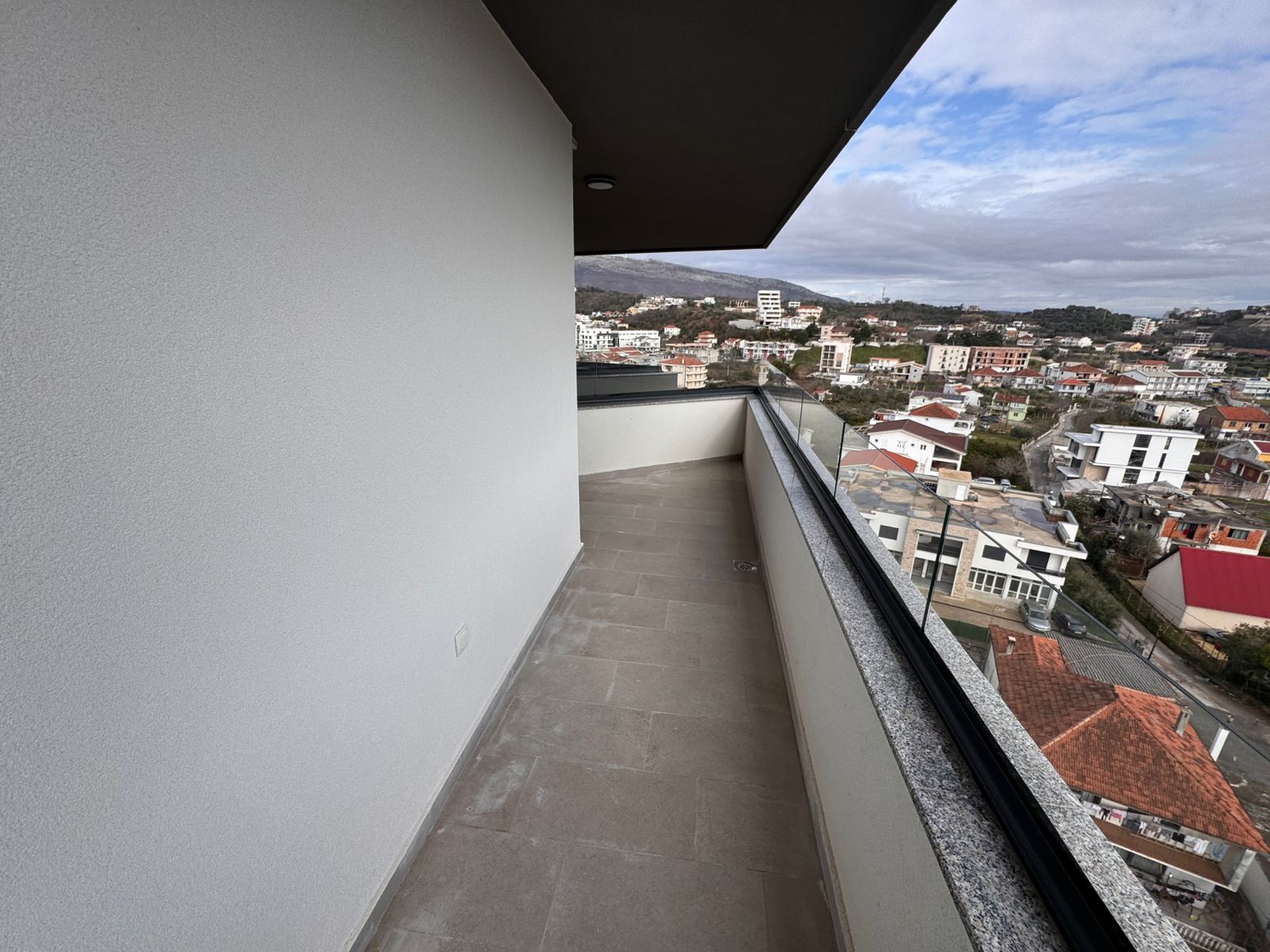 Modern balcony with sleek tile floors and glass rail, offering panoramic Ulcinj views&mdash;ideal Montenegro investment via ekosphere doo.