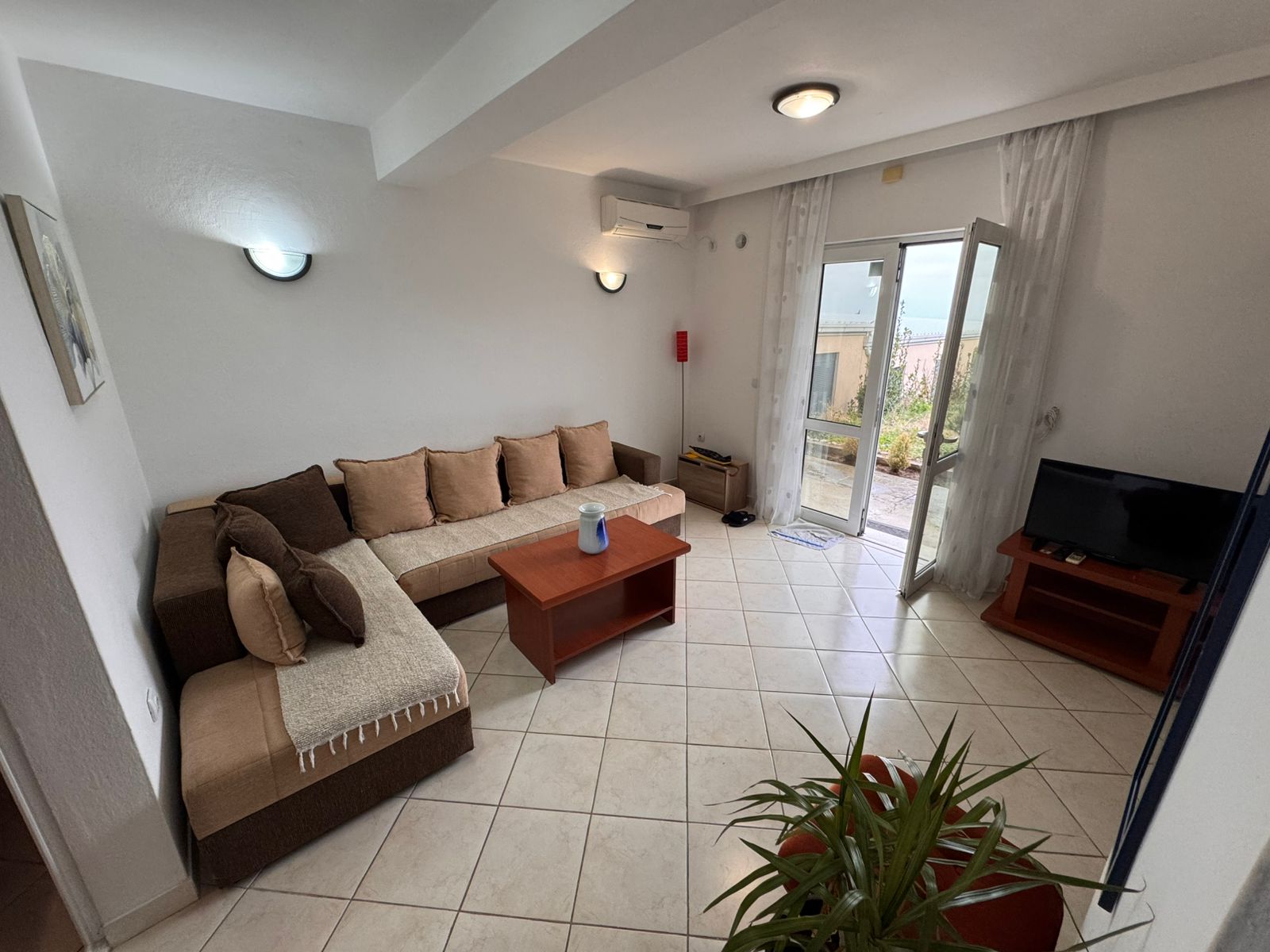 Elegant Ulcinj living room with beige sectional, wood accents, and sunny terrace access—exclusive at montenegro-listings.me by ekosphere doo.