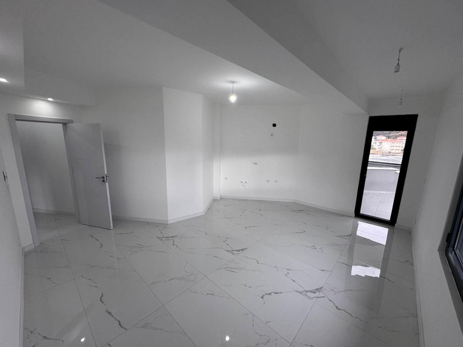 Bright, unfurnished room in Ulcinj with elegant marble-pattern tiles, white walls, balcony access&mdash;ideal investment via montenegro-listings.me.