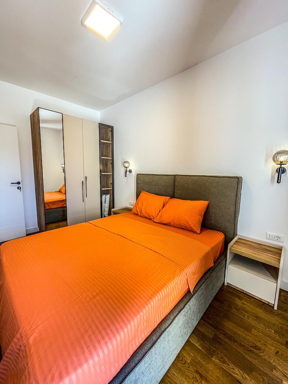 Modern bedroom in Ulcinj, Montenegro&mdash;wood floors, mirrored wardrobe, orange accents. Invest with montenegro-listings.me by ekosphere doo.