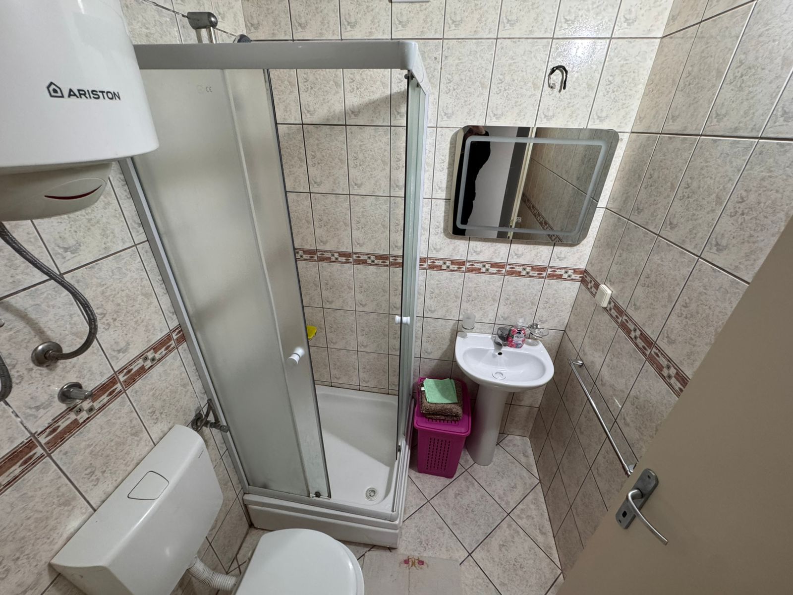 Modern tiled bathroom in Ulcinj home with corner glass shower, sink, toilet & water heater. Top Montenegro investment at montenegro-listings.me by ekosphere doo.