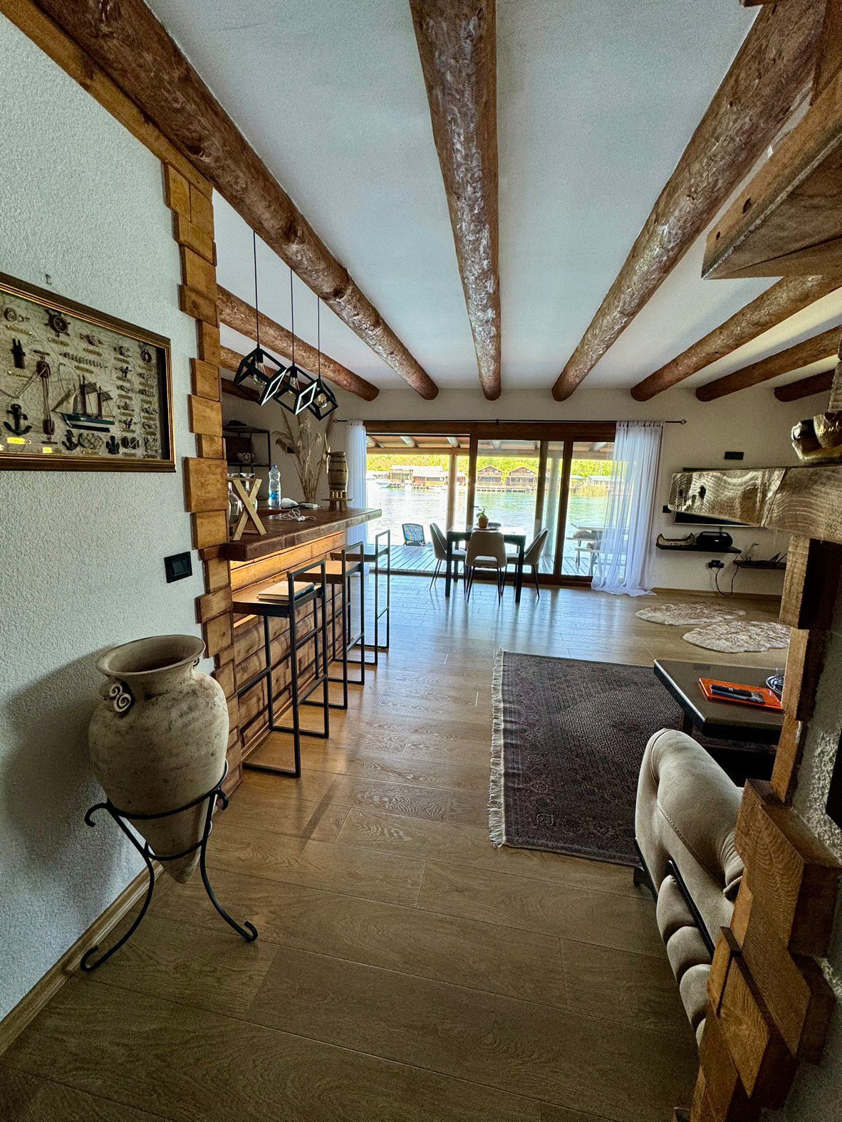 Elegant open-plan living and dining in Ulcinj with wood-beamed ceilings, bar, panoramic windows. Listed on montenegro-listings.me by ekosphere doo.