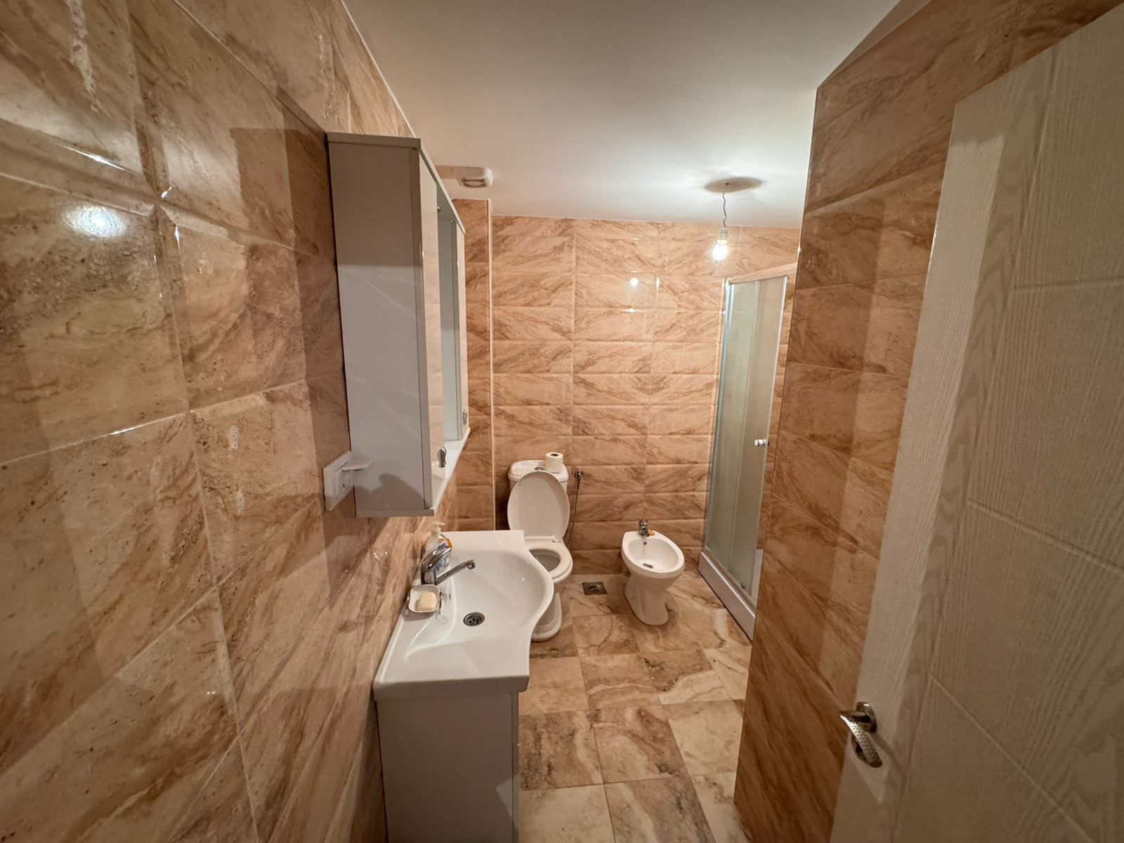 Luxurious Ulcinj bathroom with beige marble tiles, modern fixtures, glass shower. Listed by montenegro-listings.me, ekosphere doo.