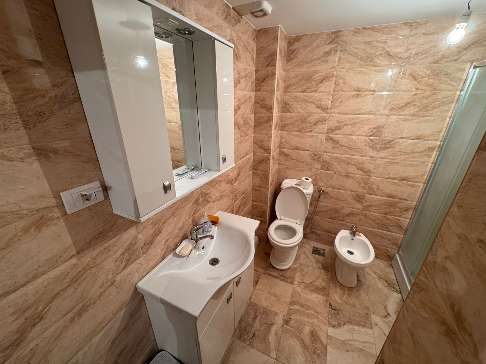 Modern bathroom in Ulcinj with marble-style tiles, sink, bidet, shower. Invest in luxury property at montenegro-listings.me by ekosphere doo.