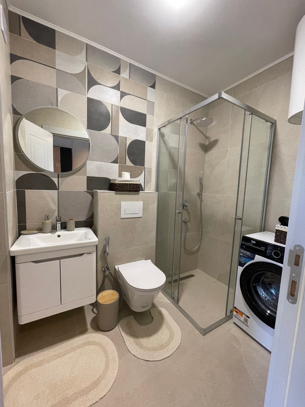 Elegant modern bathroom in Ulcinj, with premium beige tiles, luxury fixtures, washer, and walk-in shower&mdash;exclusive at montenegro-listings.me.