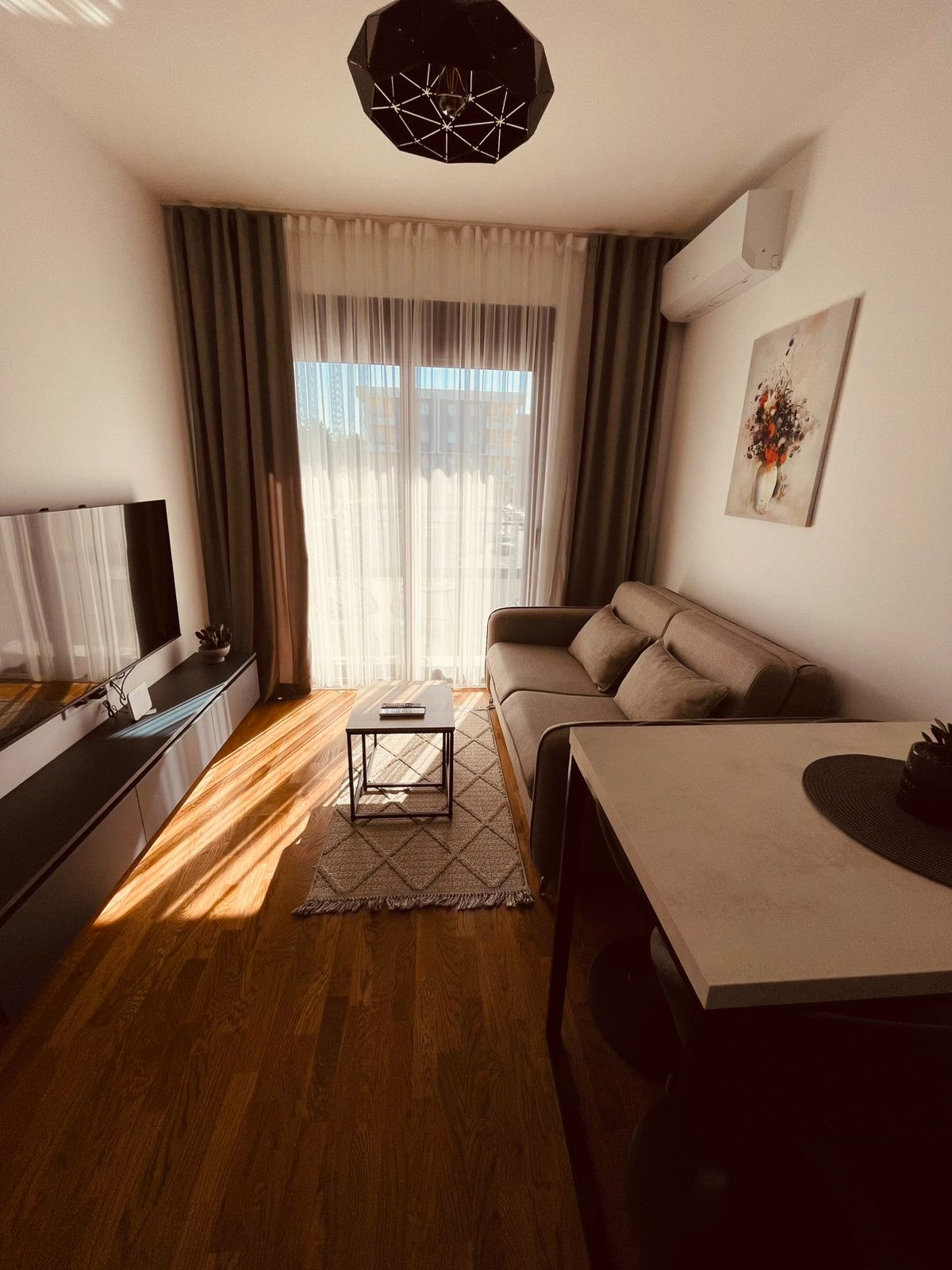Bright living room with wood floors, modern furnishings, and sunlit windows—invest in Ulcinj real estate via montenegro-listings.me.