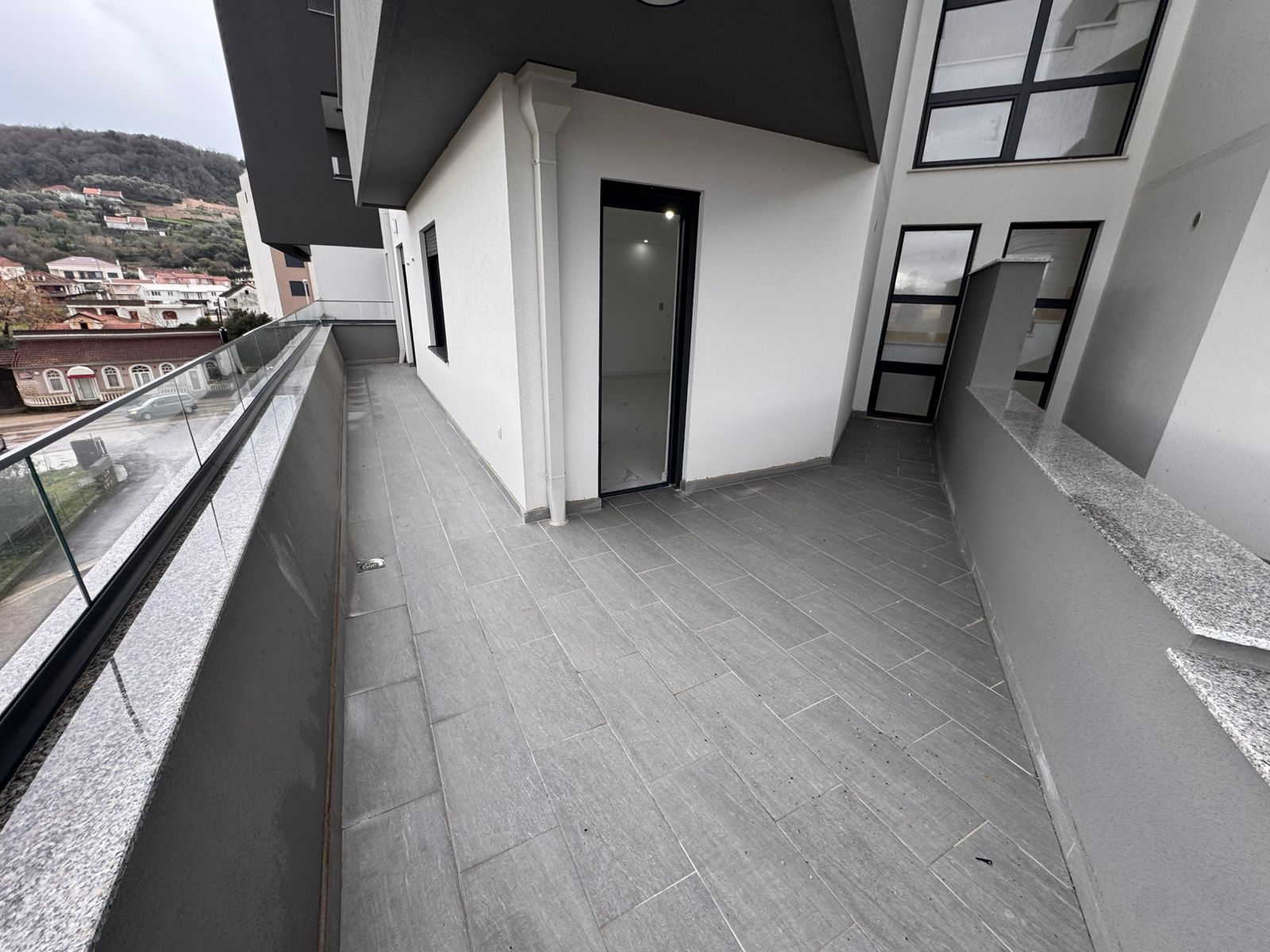 Modern balcony in Ulcinj with gray tiles, glass railing, large windows & views&mdash;ideal real estate by ekosphere doo on montenegro-listings.me.