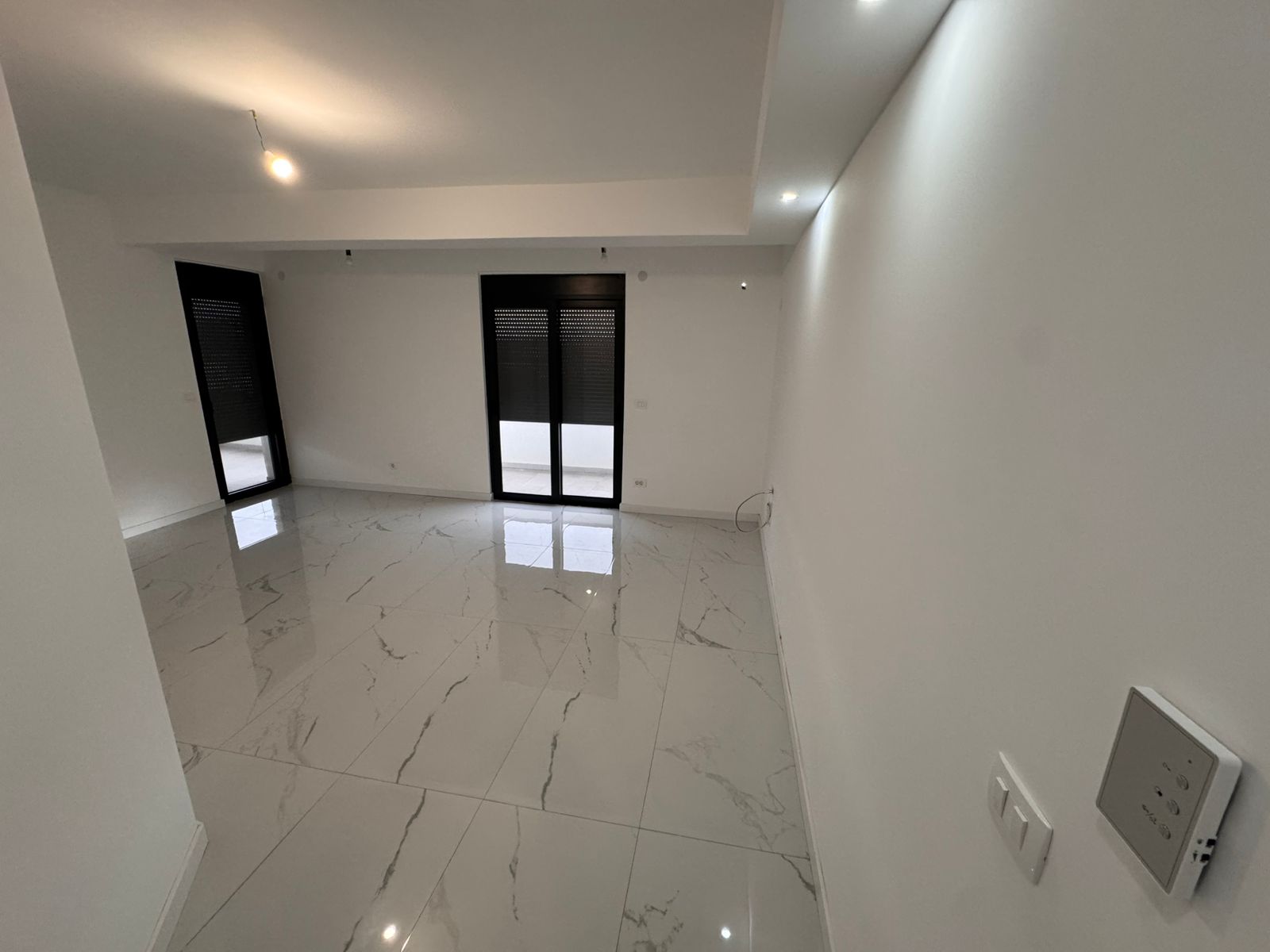 Spacious modern room in Ulcinj, Montenegro; sleek white walls, luxury veined floor tiles, large windows. Exclusive at montenegro-listings.me by ekosphere doo.