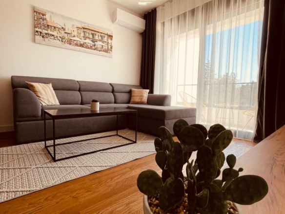 Elegant Ulcinj apartment for sale: modern living room, gray sectional, sunlit windows; prime Montenegro property at montenegro-listings.me.