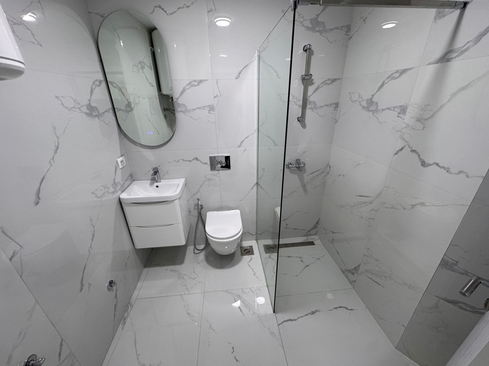 Luxurious Ulcinj bathroom with marble tiles, sleek fixtures, and glass shower&mdash;exclusive Montenegro property by ekosphere doo.
