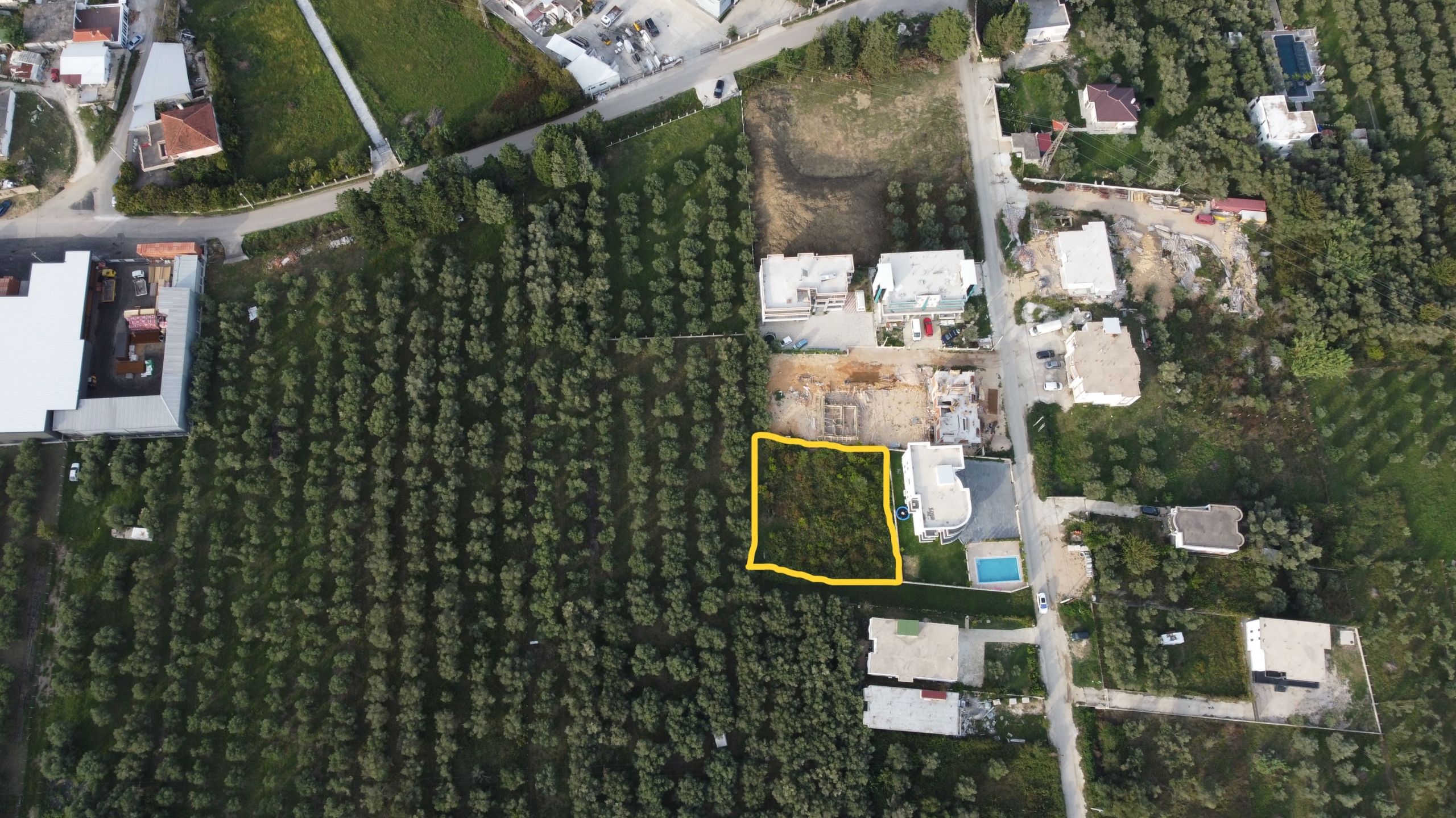 Prime aerial view of Ulcinj, Montenegro: exclusive rectangular investment plot outlined in yellow amid lush greenery and housing.